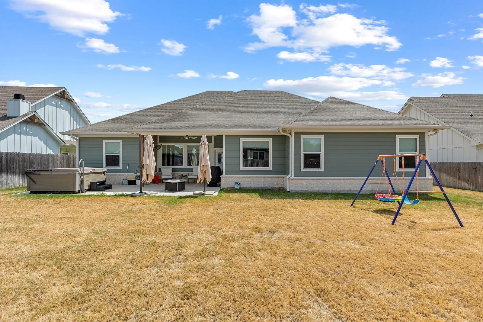 Spacious single-story residence with a covered rear porch, expansive fenced yard with level landscaping, and a detached storage shed