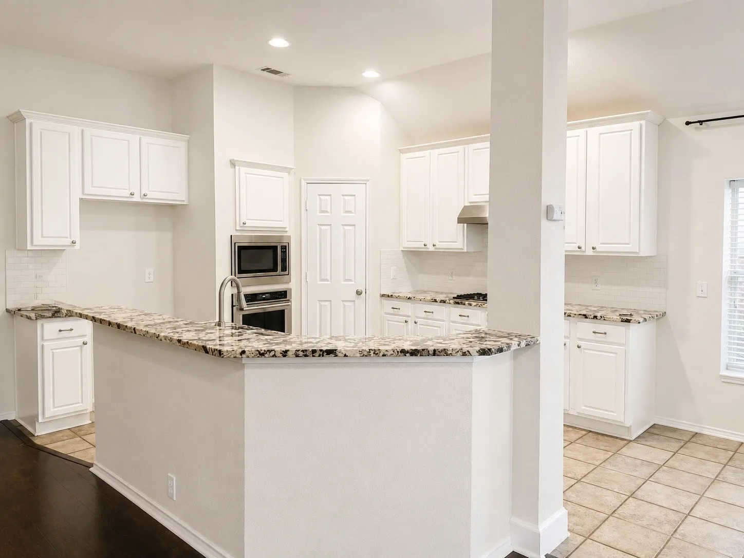 Kitchen featuring white cabinetry, granite countertops, stainless steel appliances, and recessed lighting