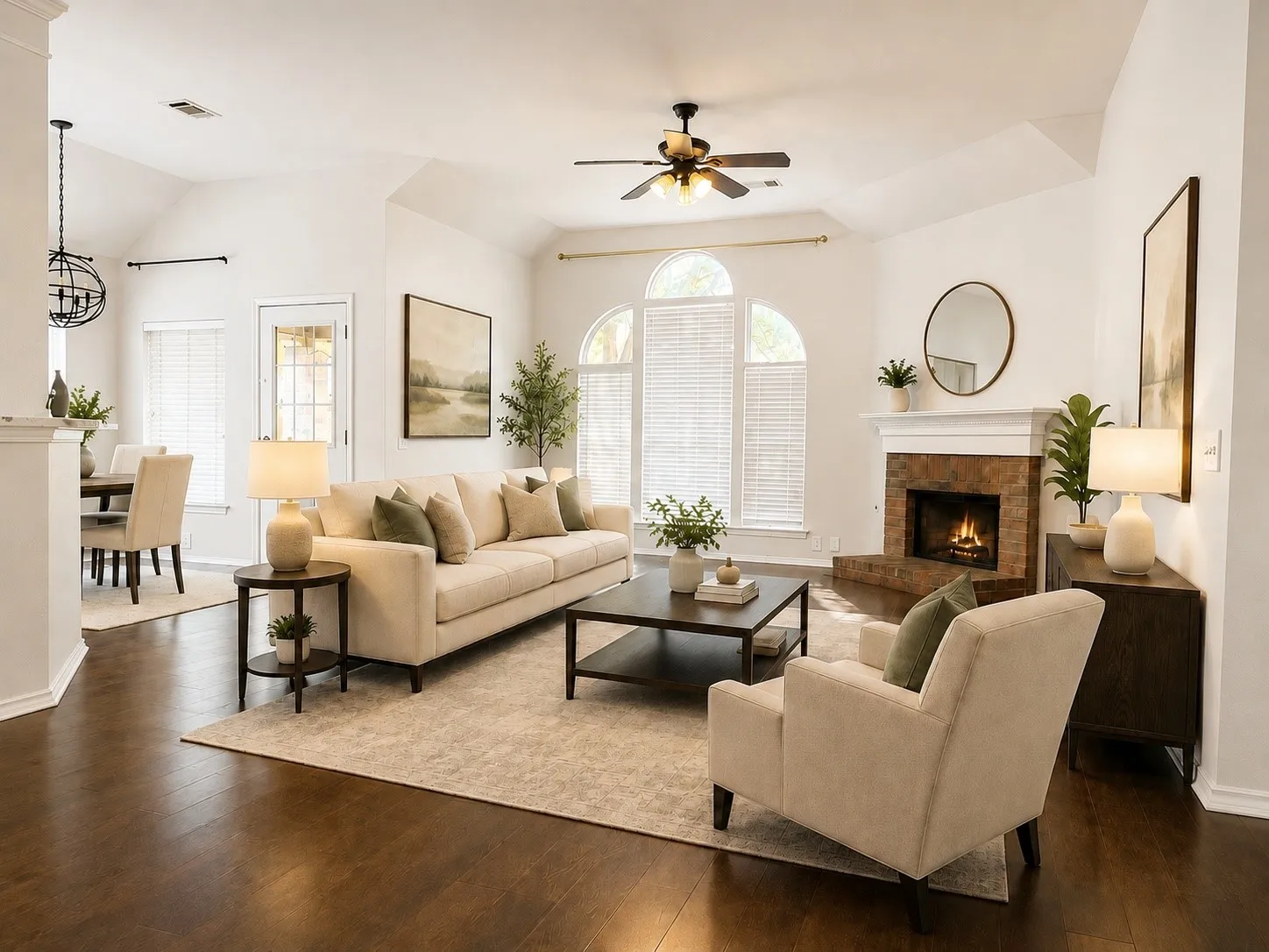 Vaulted ceilings, wood-finish flooring, a stone-surround fireplace, arched window, and a ceiling fan