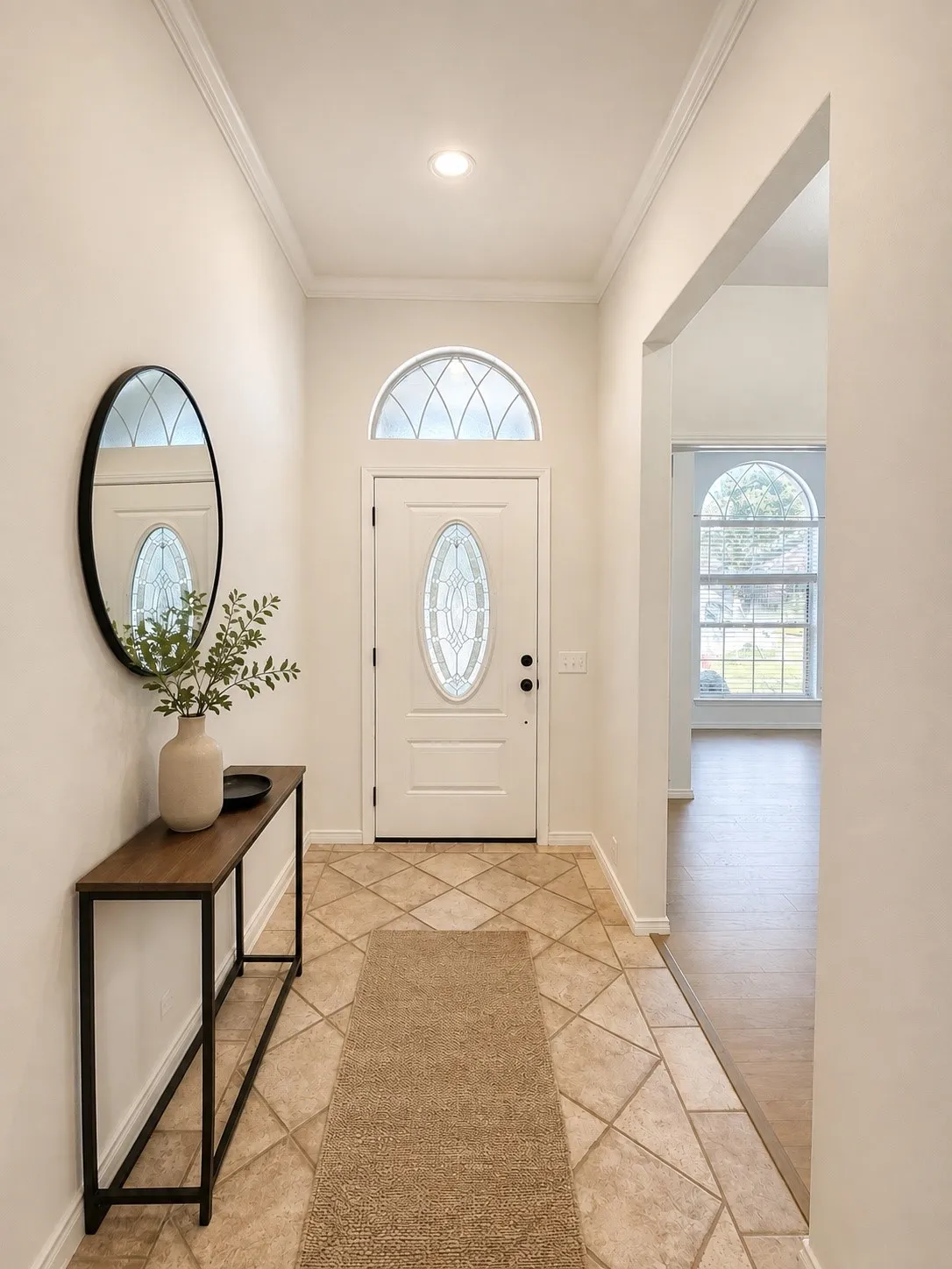 Entryway featuring a white front door with an oval glass insert, a transom window, and crown molding