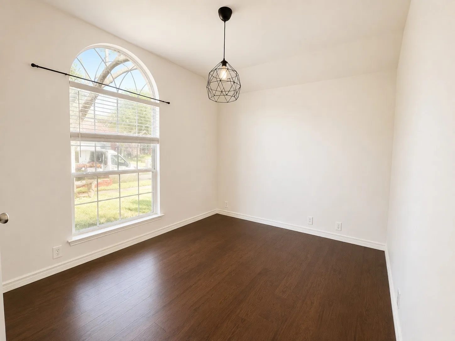 Vaulted ceiling with a contemporary pendant light fixture, arched window with horizontal blinds, and dark wood-finish flooring