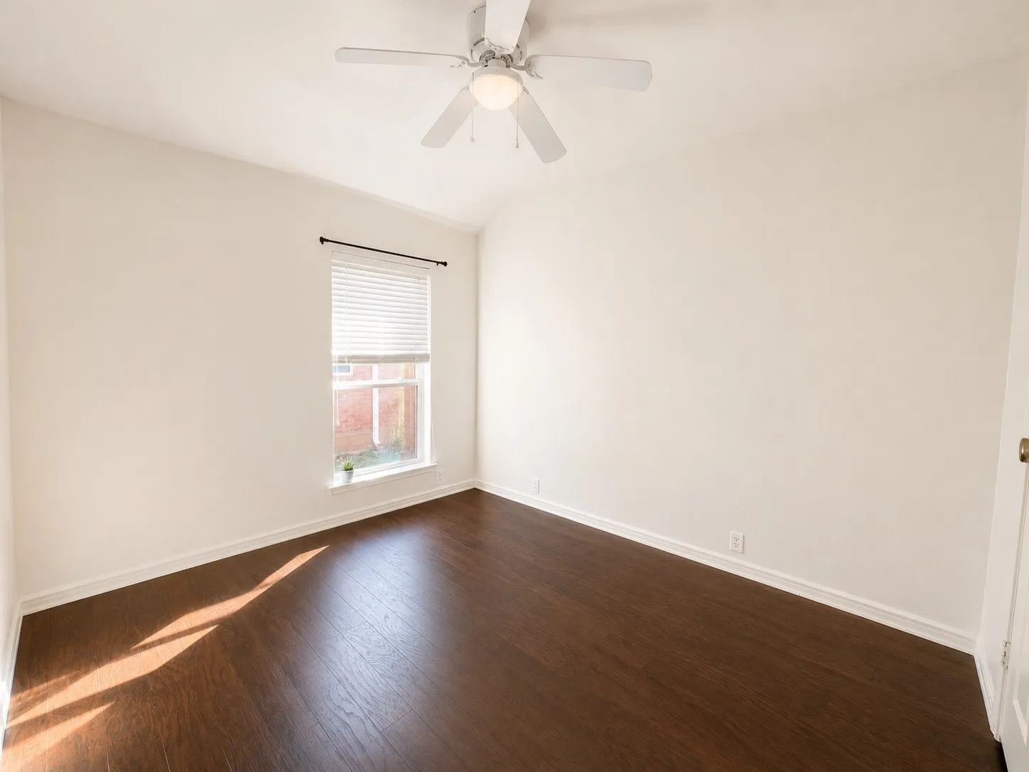 Vaulted ceiling, ceiling fan with integrated lighting, wood-finish flooring, white walls, and a window with blinds