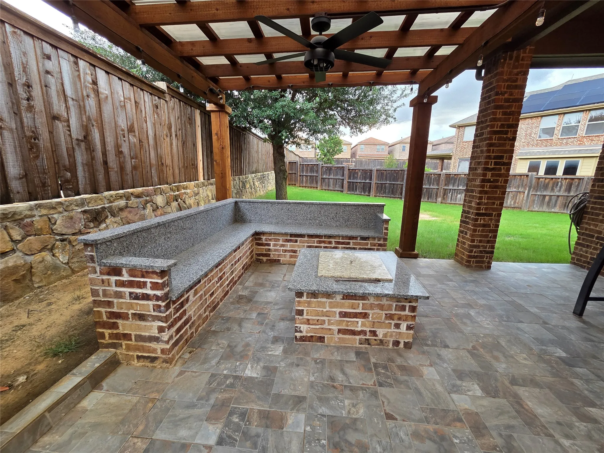 Covered outdoor patio featuring a pergola, ceiling fan, and brick columns