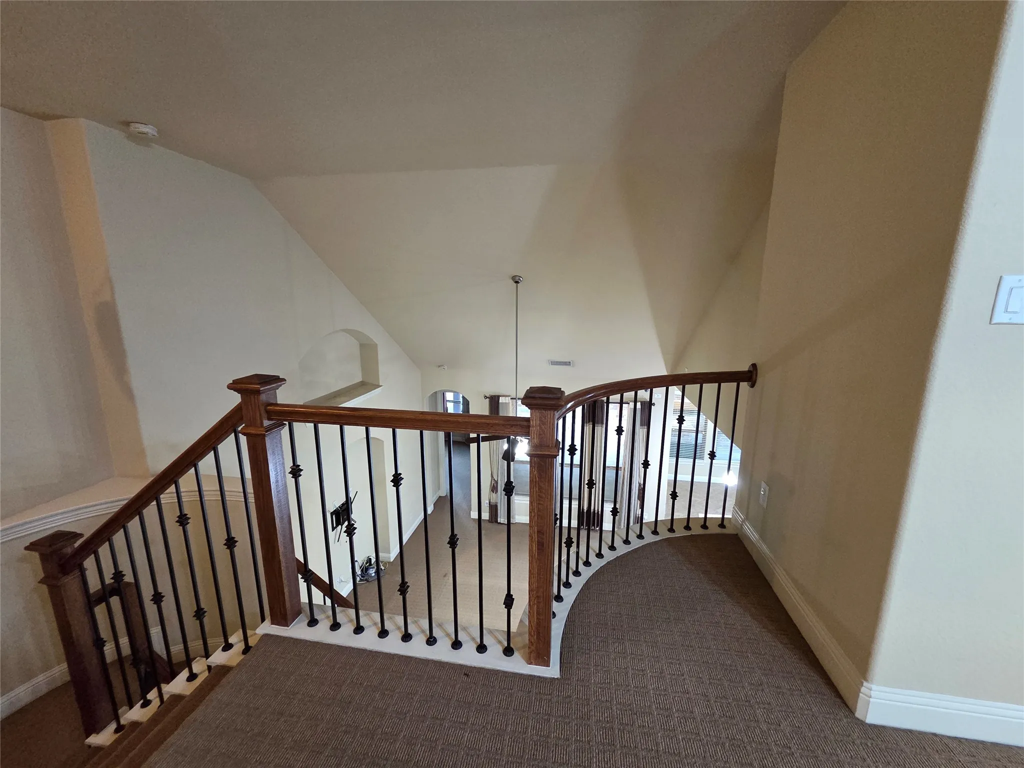 Carpeted landing with wood railing and black wrought iron spindles
