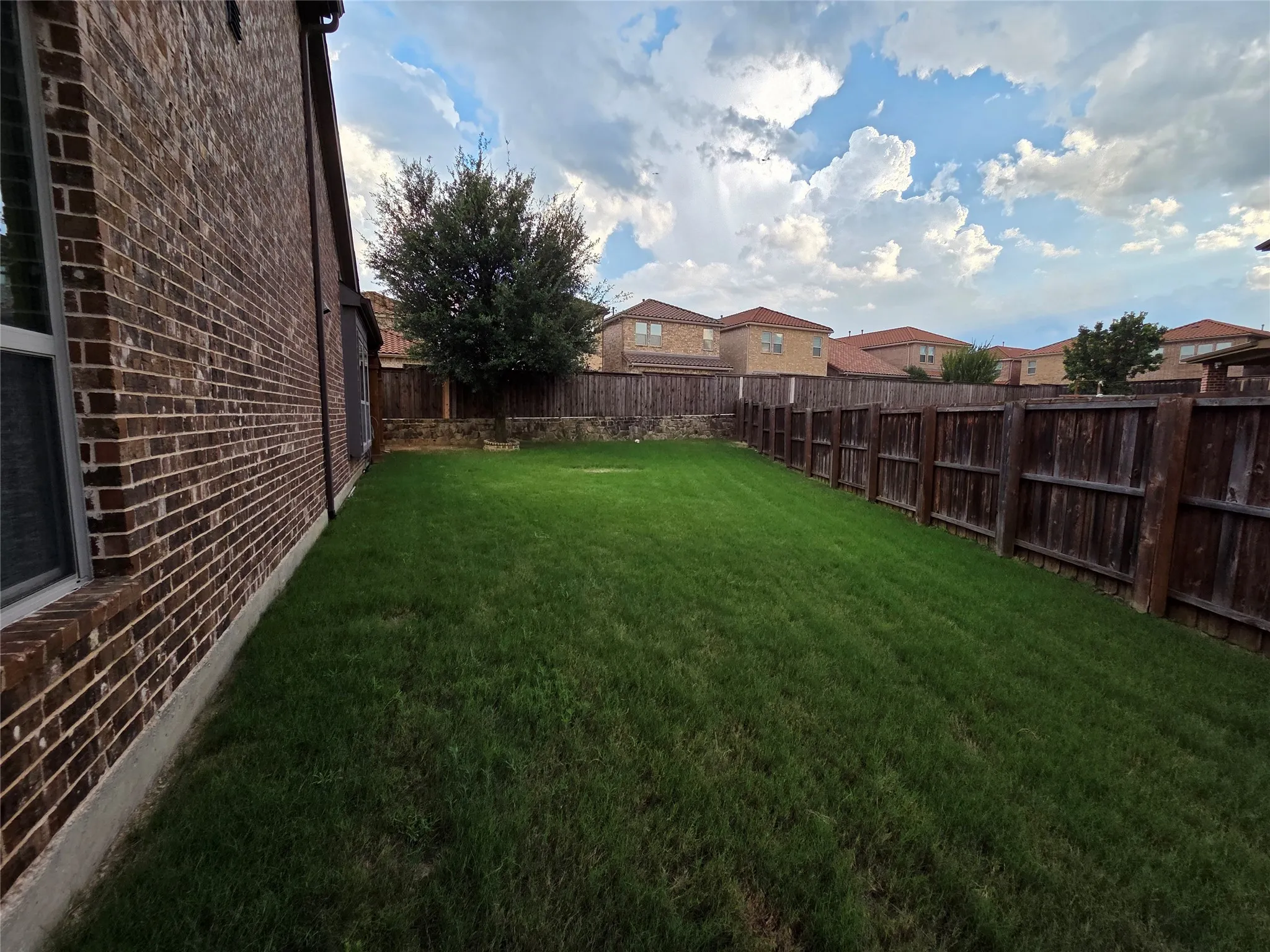 Expansive grass yard bordered by a wood privacy fence