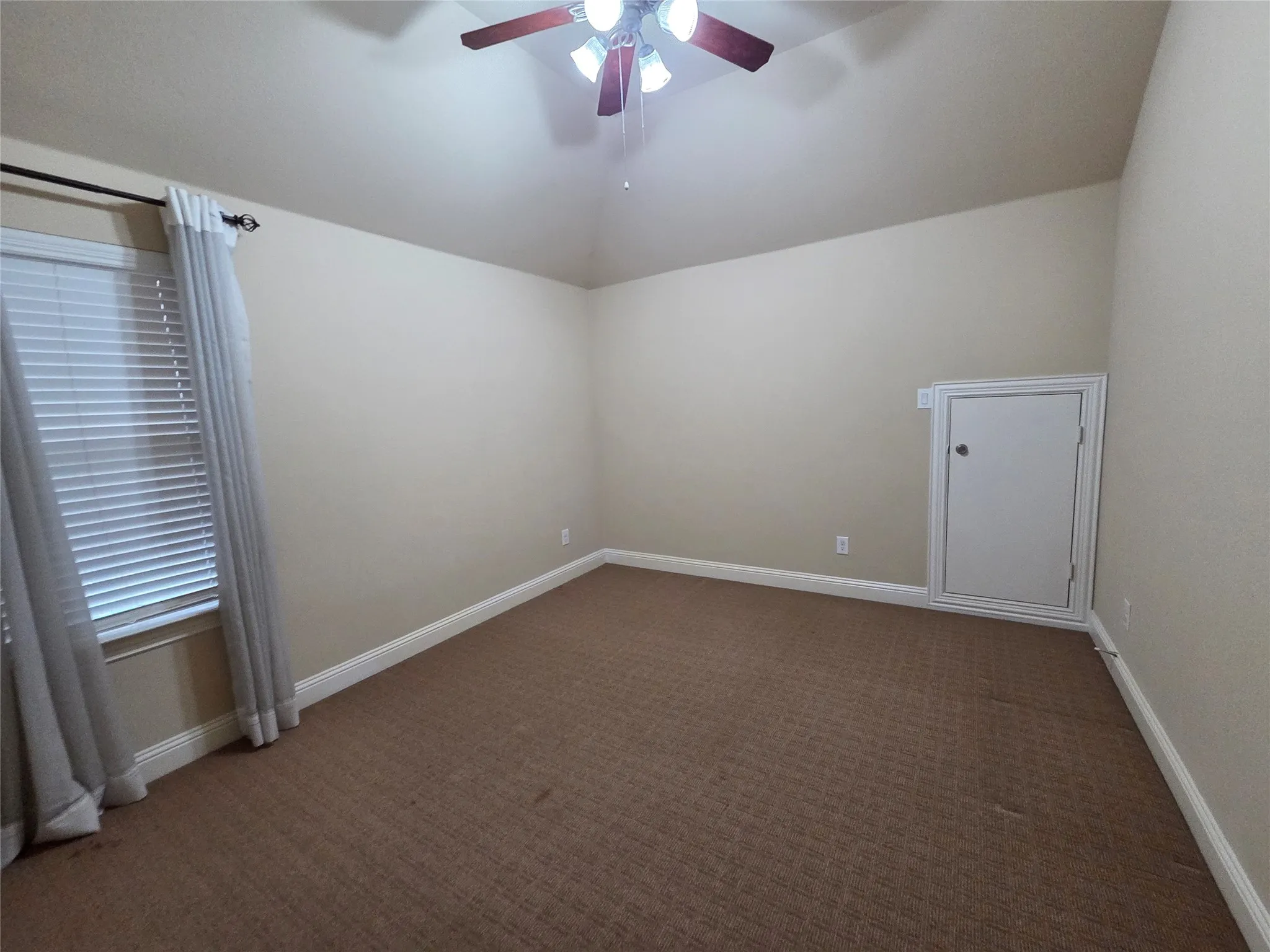 Vaulted ceiling with a ceiling fan light fixture, window with blinds, wall-to-wall carpeting, and a built-in wall access panel