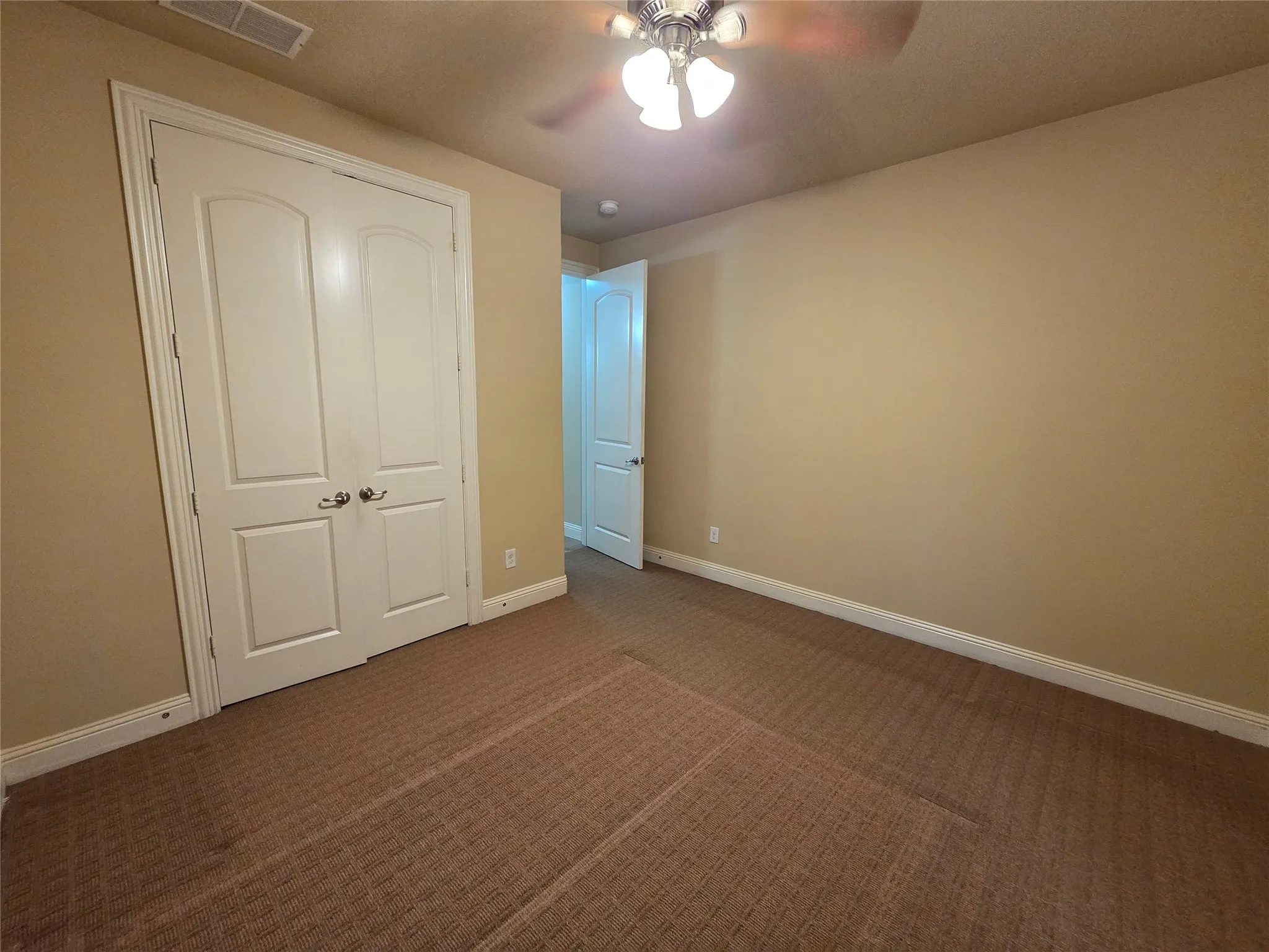 Carpeted room featuring a ceiling fan with integrated lighting, a double-door closet, and white baseboards