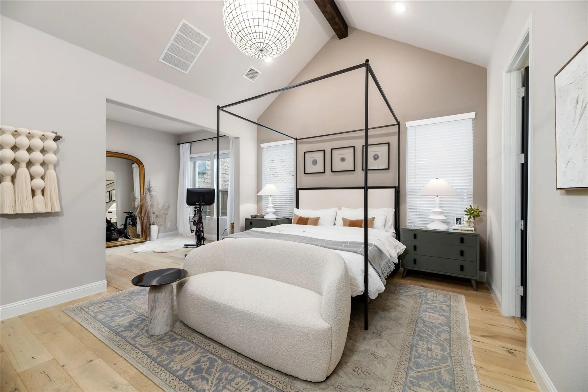 Vaulted ceiling with exposed wood beam, large overhead light fixture, wood-finish flooring, and window with blinds