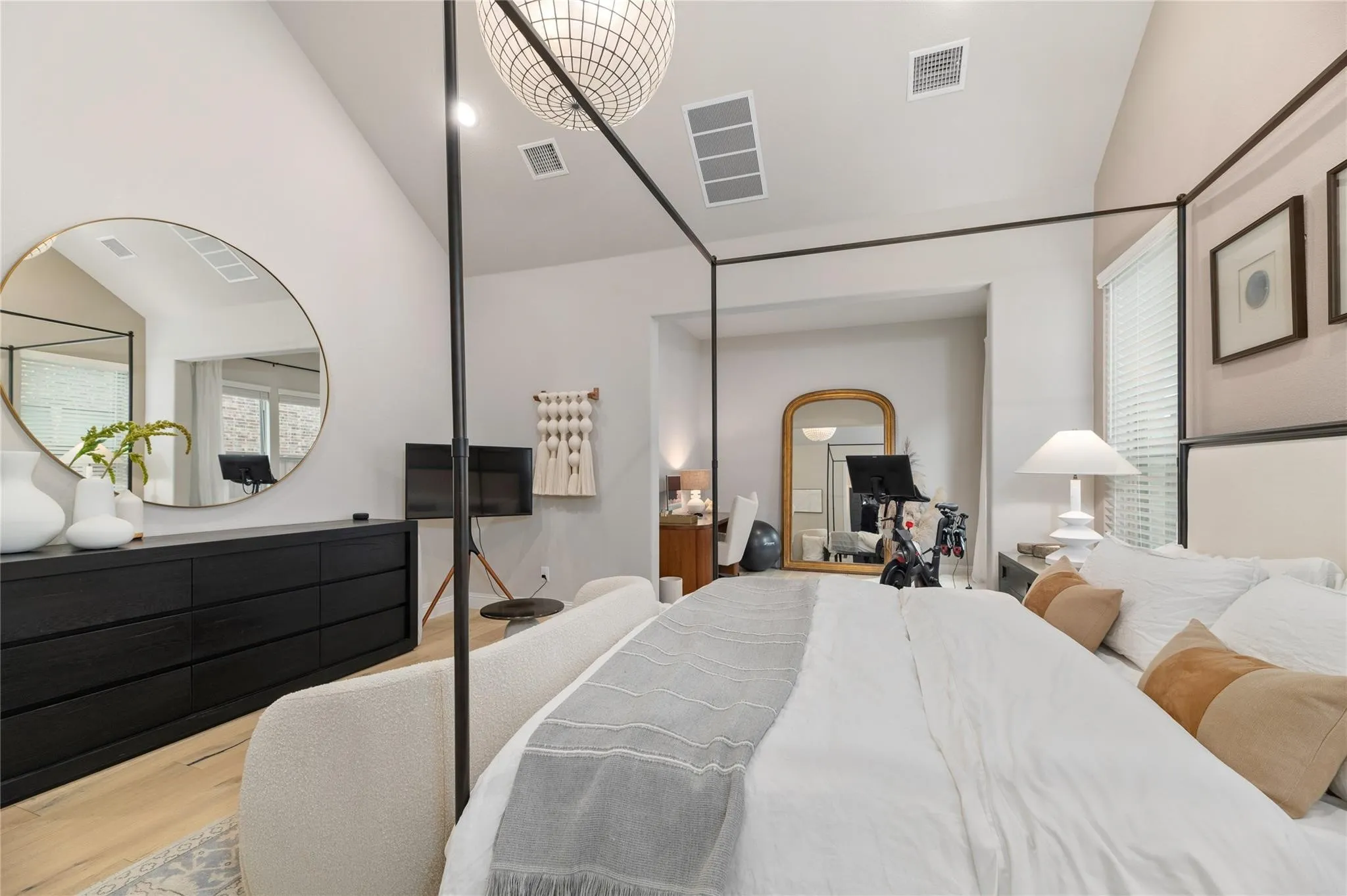 Vaulted ceiling with a contemporary chandelier, light wood-finish flooring, and a large window with blinds
