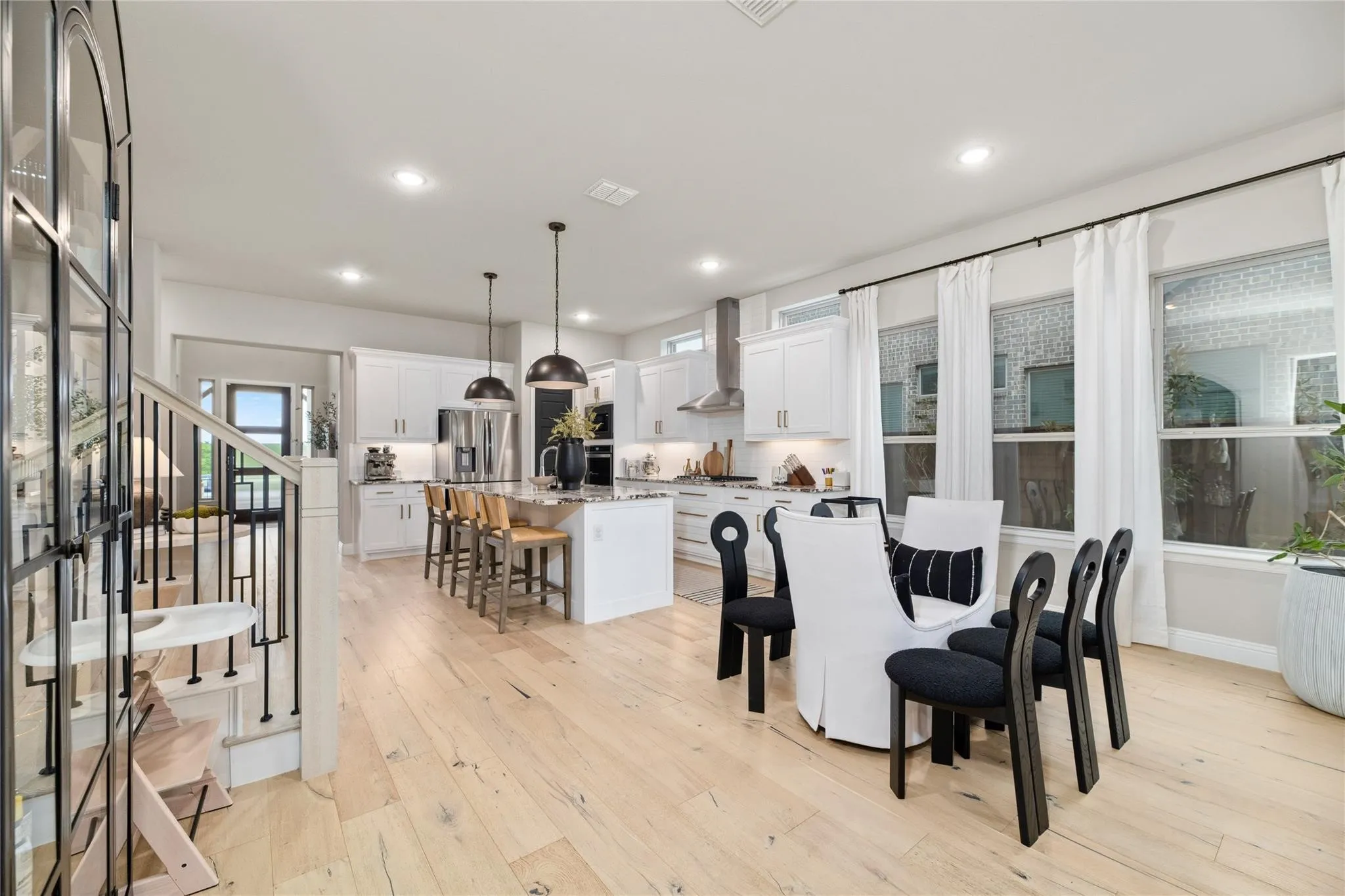 Open-concept living space featuring wood-finish flooring, a kitchen island with seating, pendant lighting, built-in cabinetry, and multiple windows