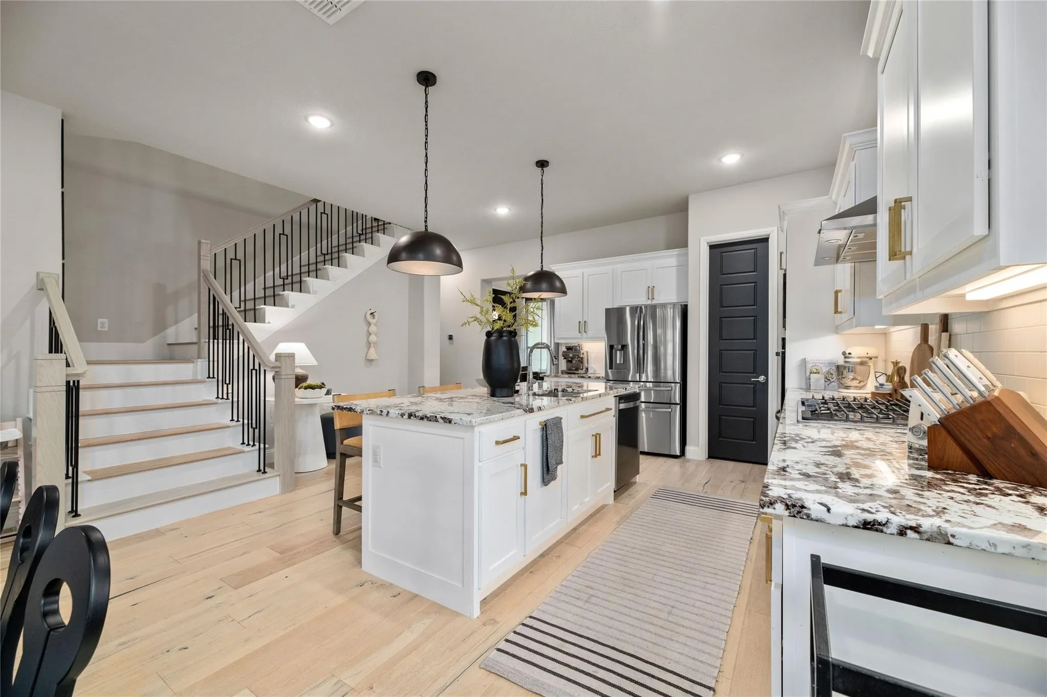 Open-concept kitchen featuring an island with seating, stainless steel appliances, and light wood-finish flooring