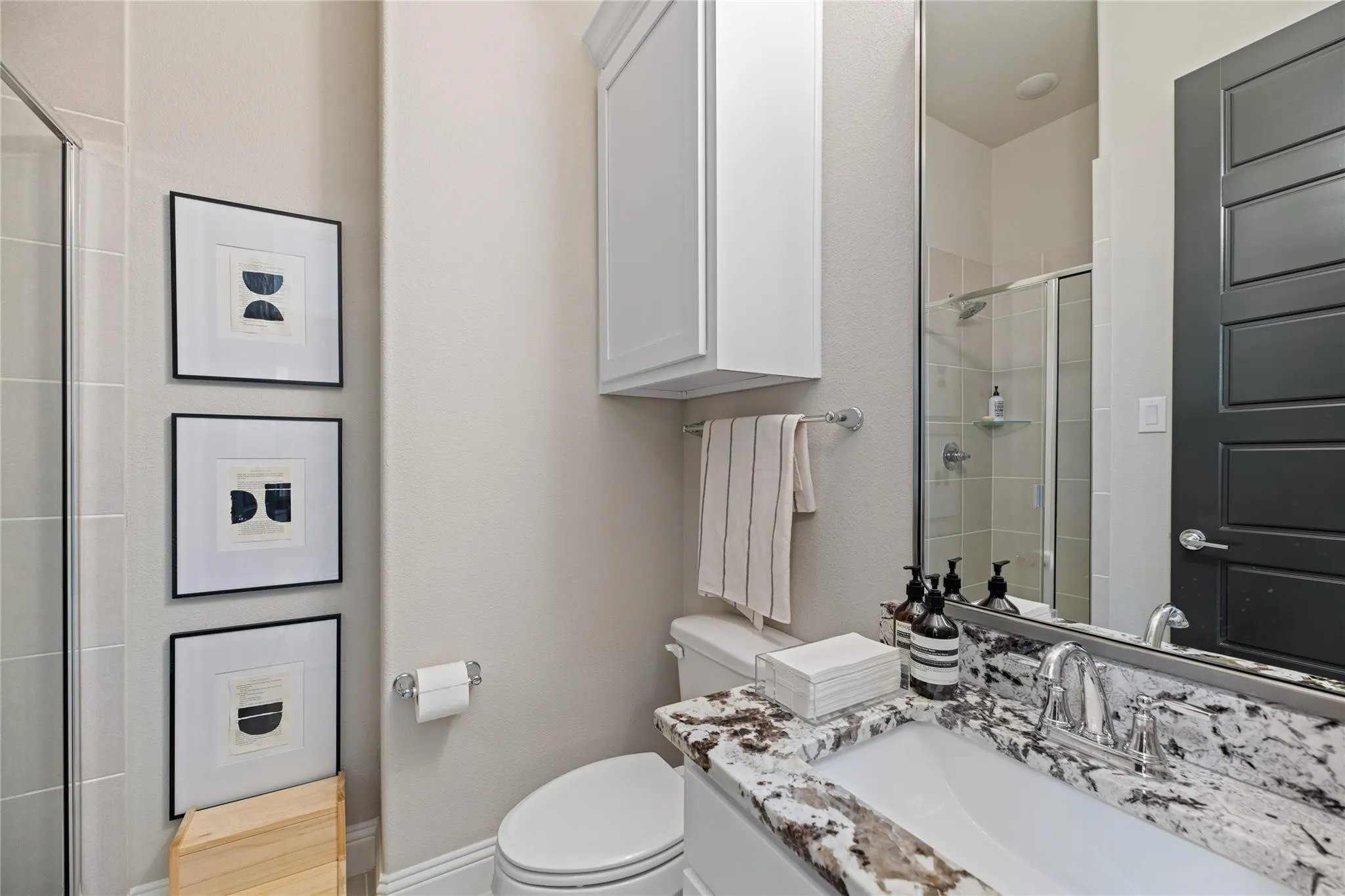 Vanity with a patterned stone countertop, single basin sink, and chrome faucet
