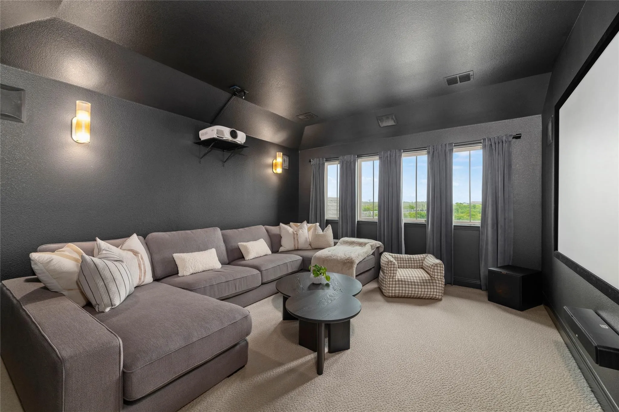 Dedicated media space featuring a mounted projector, large projection screen, and integrated wall sconces