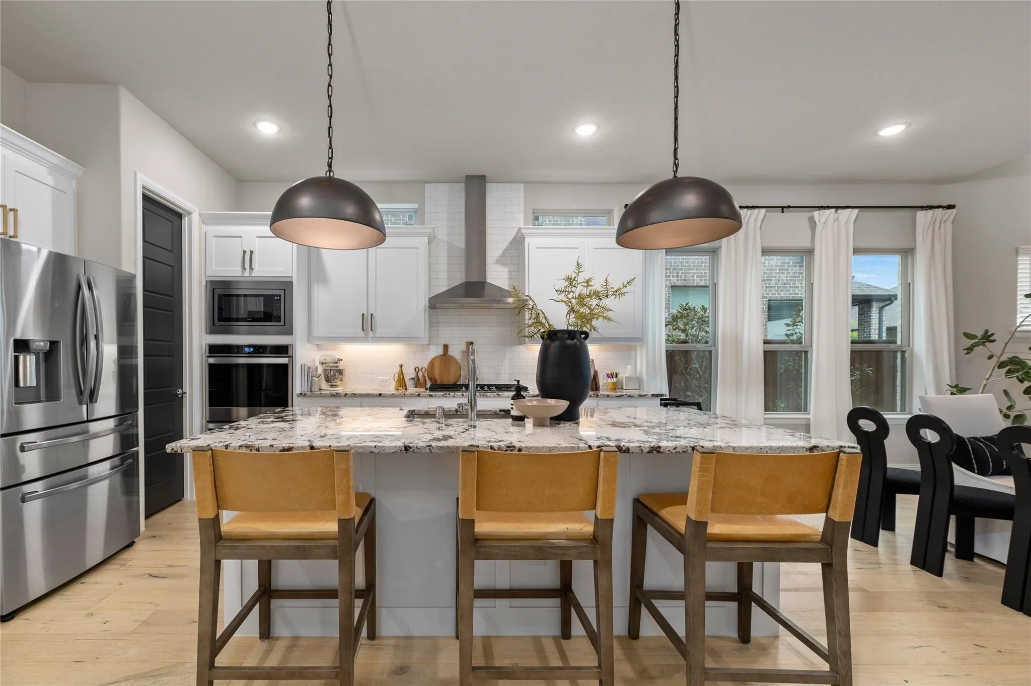 Kitchen featuring an integrated stainless steel appliance package, white cabinetry, a center island with a stone-finish countertop, and recessed lighting
