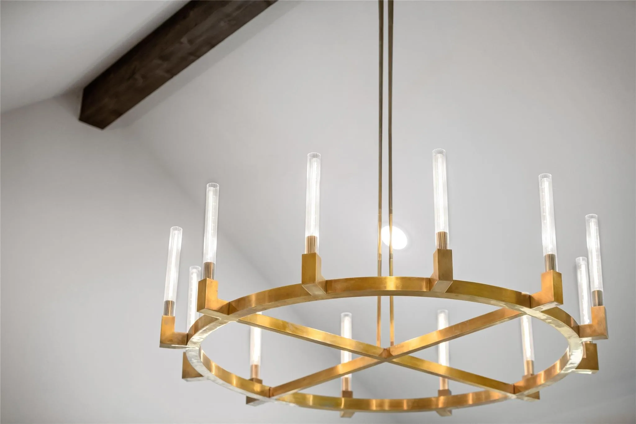 Contemporary brass chandelier with multiple tube-shaped lights and a prominent ceiling beam