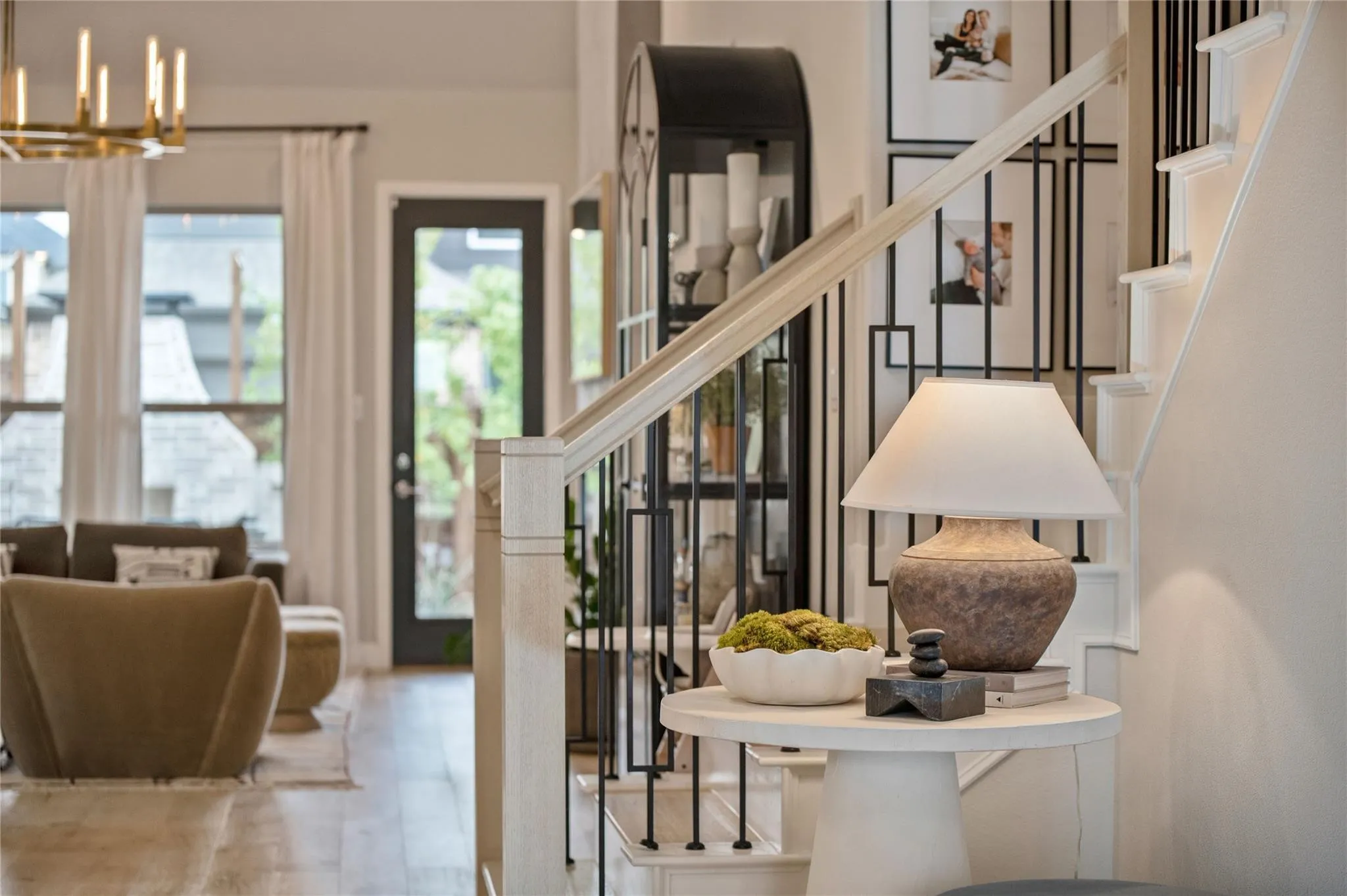 Hardwood-finish flooring, staircase with wrought iron balusters, high ceilings, and abundant natural light from multiple windows and a glass-paneled door