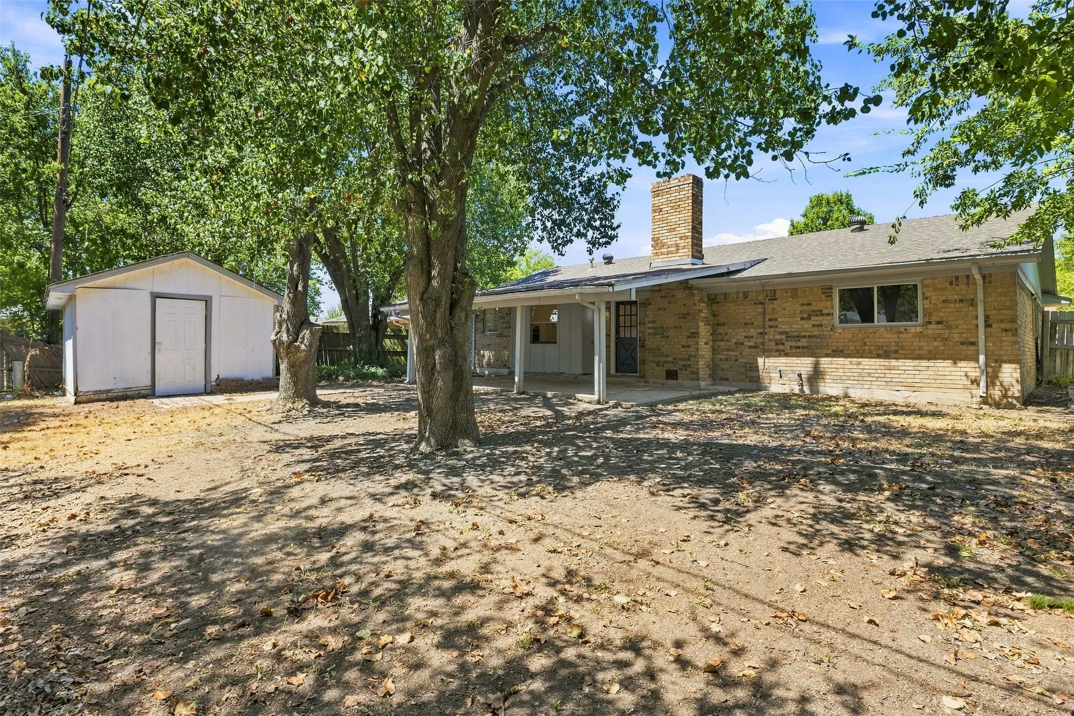 Large backyard with covered porch and storage shed that stays
