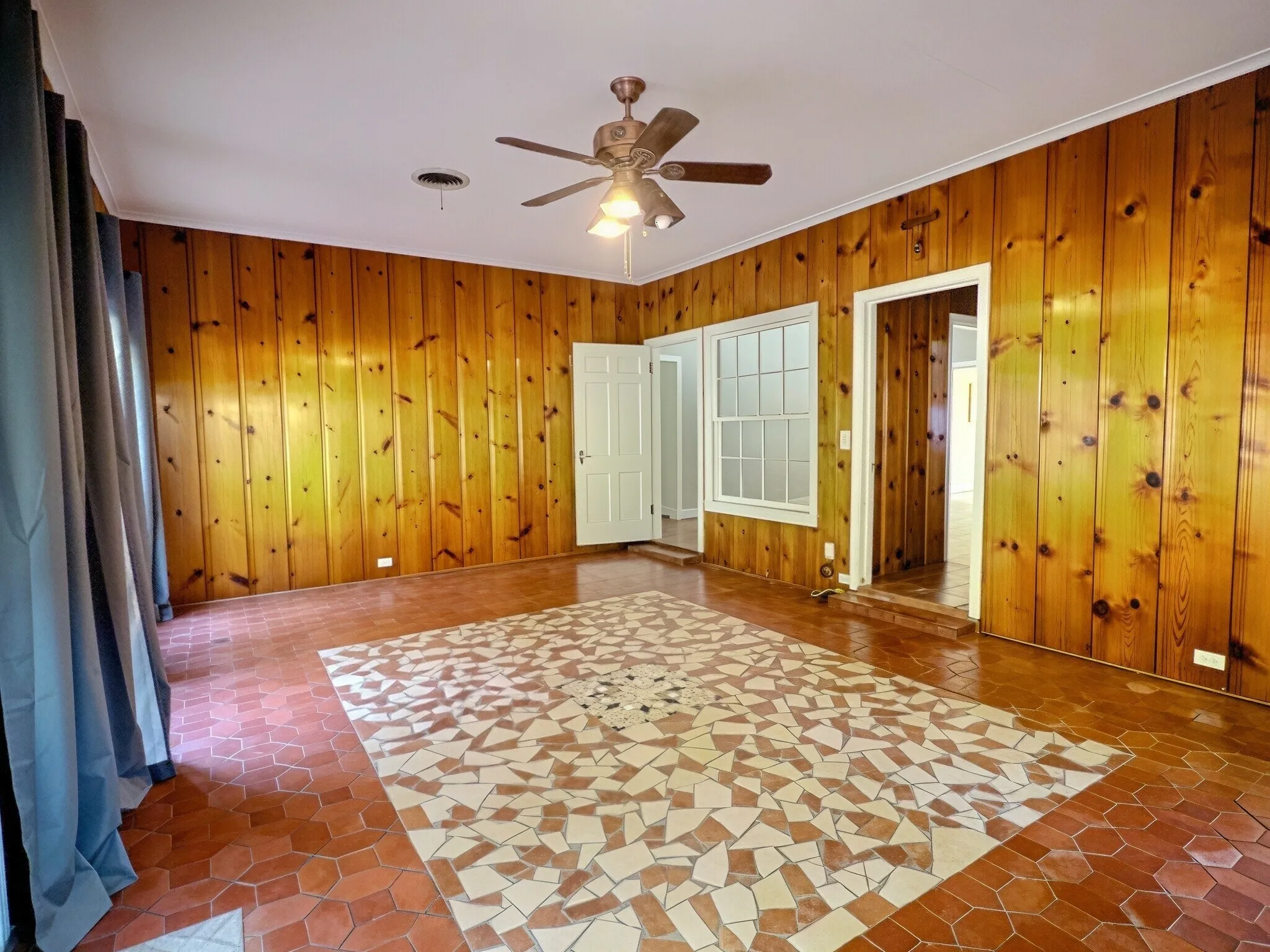 Wood paneling throughout, mosaic tile flooring, ceiling fan with integrated lighting, and a white framed window