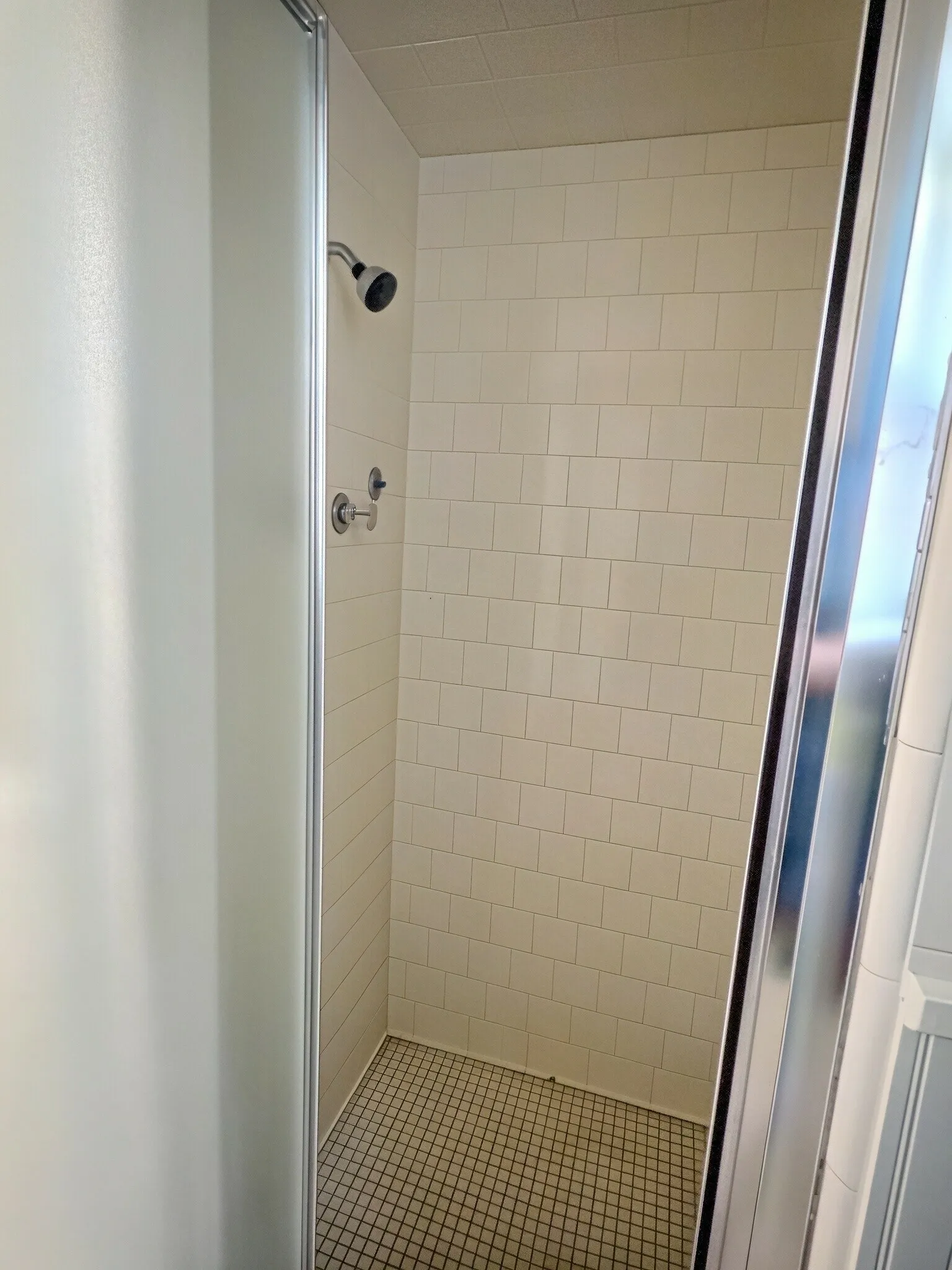Shower stall featuring subway tile walls, a matte black showerhead, and a mosaic tile floor