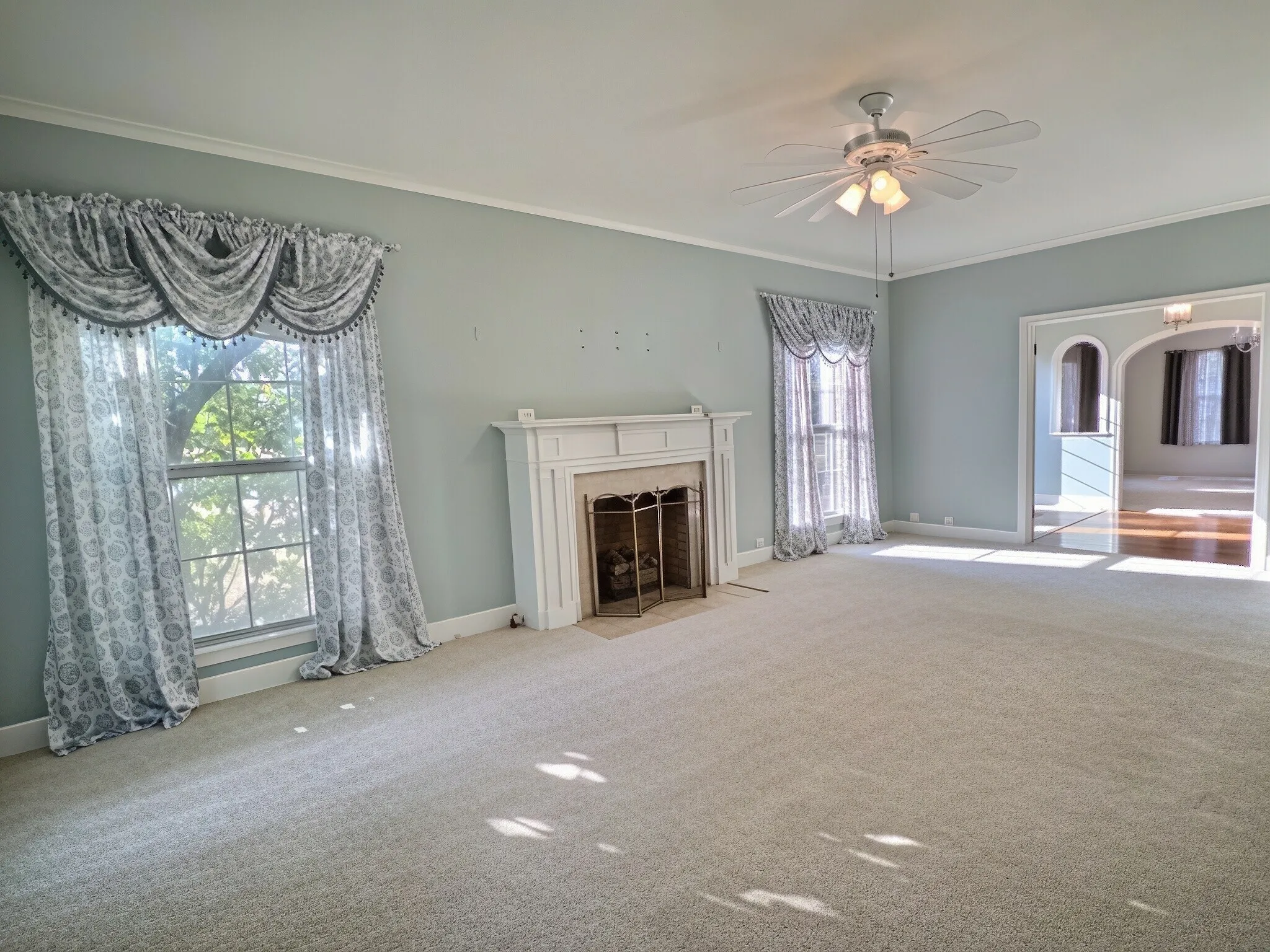 Built-in fireplace with a decorative mantel, arched entryway, and neutral carpeting