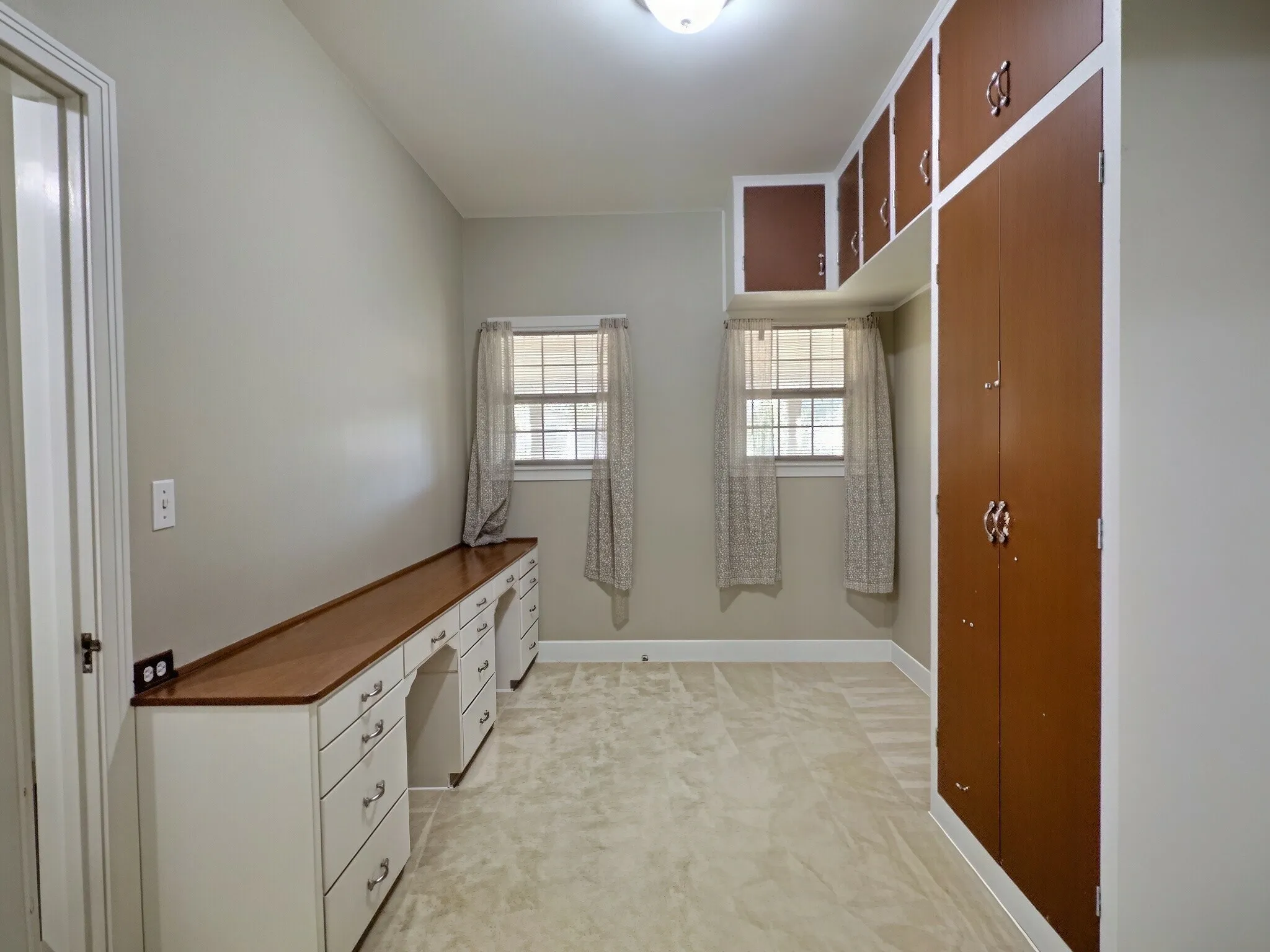 Built-in cabinetry with wood-finish countertop, two windows with natural light, and neutral wall paint