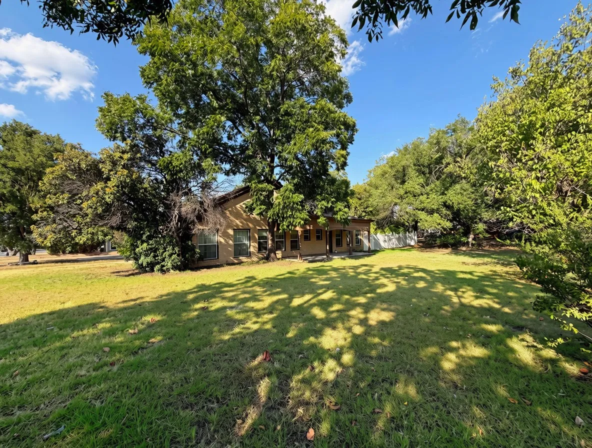 Expansive green lawn with mature trees providing shade
