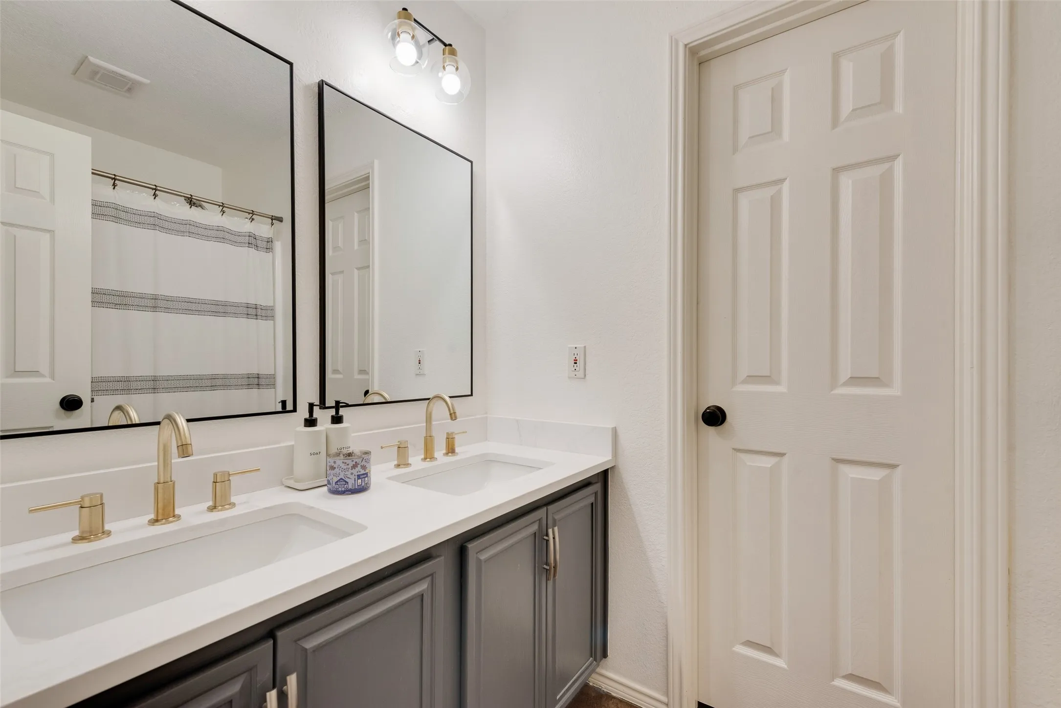 Dual vanity with undermount sinks, gold-tone fixtures, and dark gray cabinetry