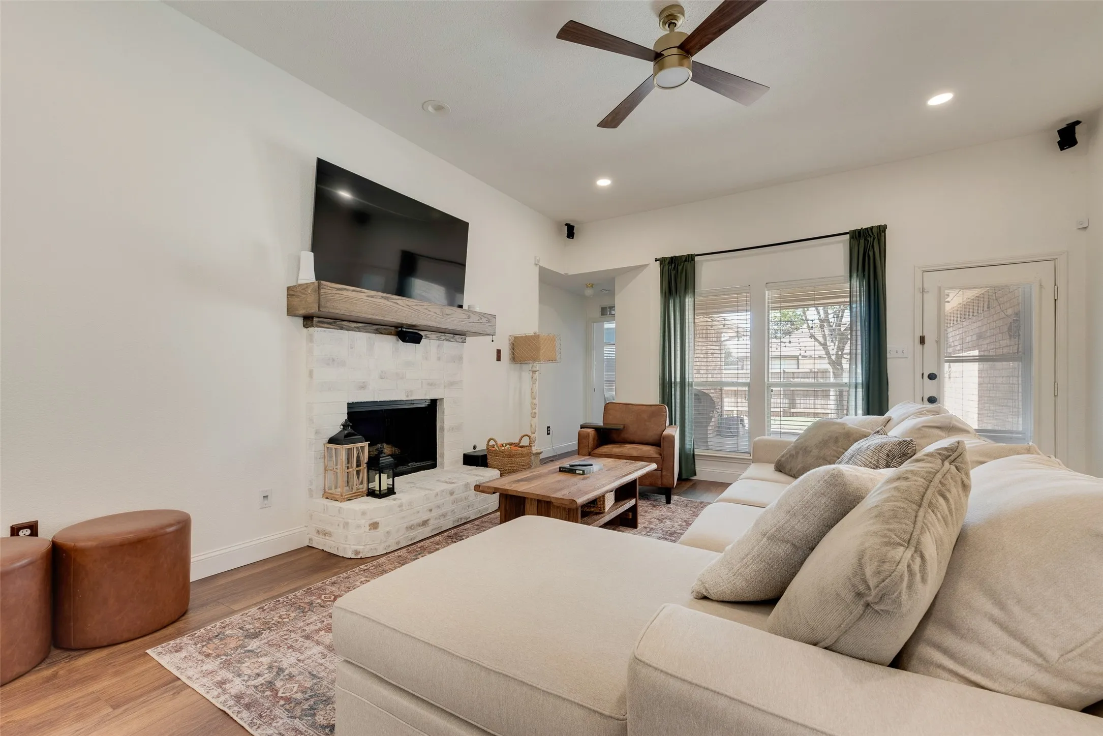 Brick fireplace with a wood mantel, wood-finish flooring, recessed lighting, and a ceiling fan