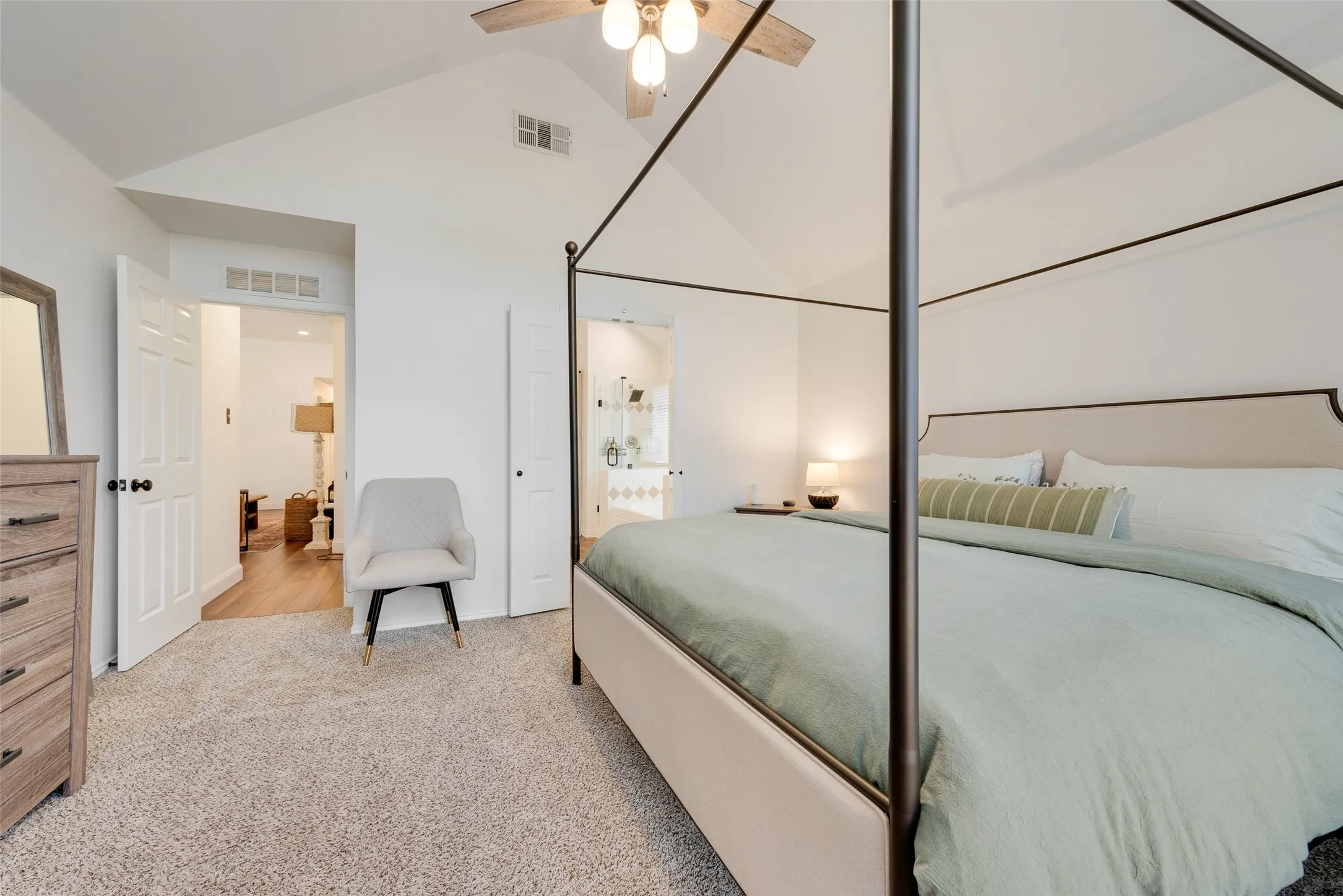 Vaulted ceiling with a wood-finish ceiling fan, carpeted flooring, and a neutral color palette