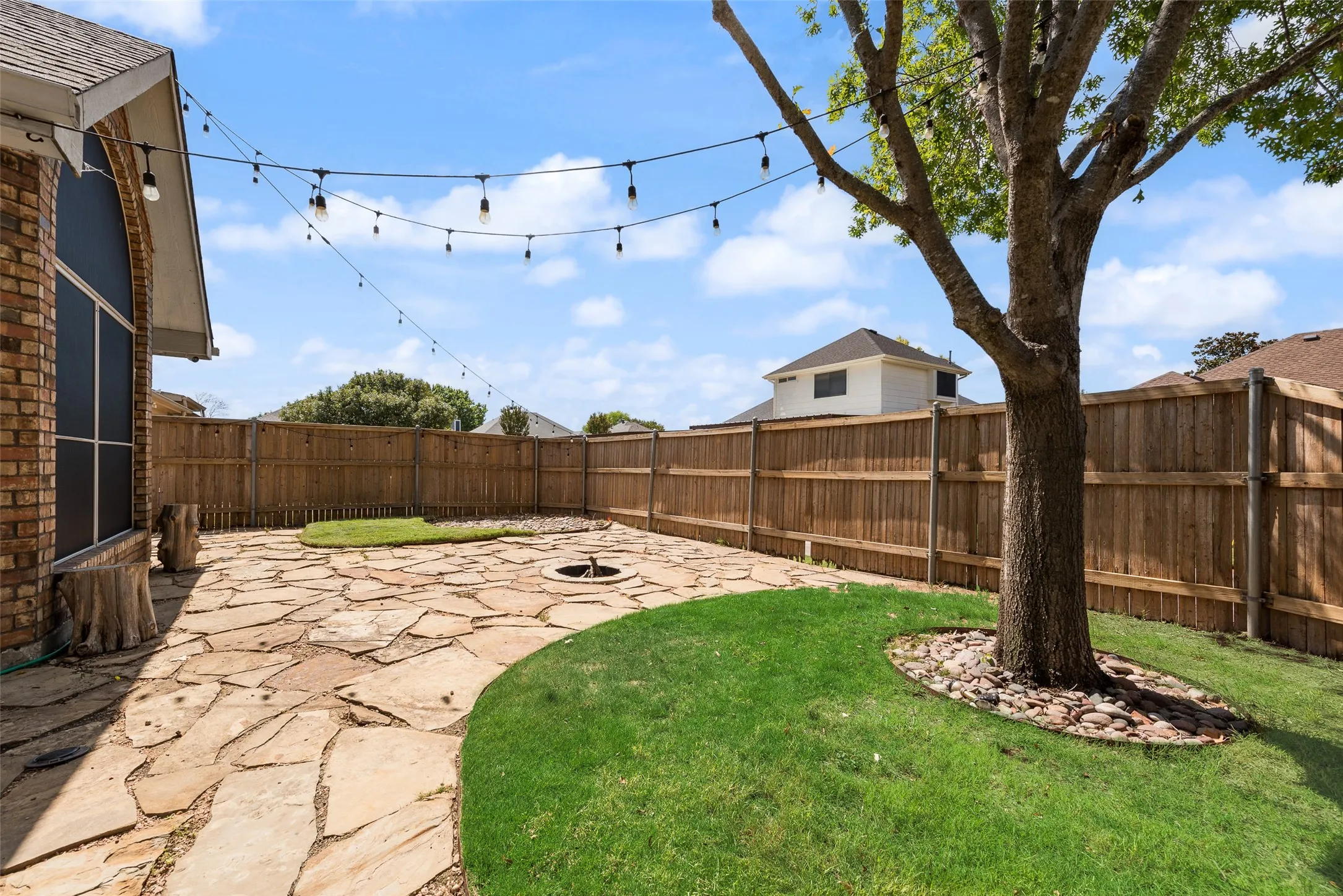Private backyard featuring a flagstone patio, wood privacy fencing, and a built-in fire pit