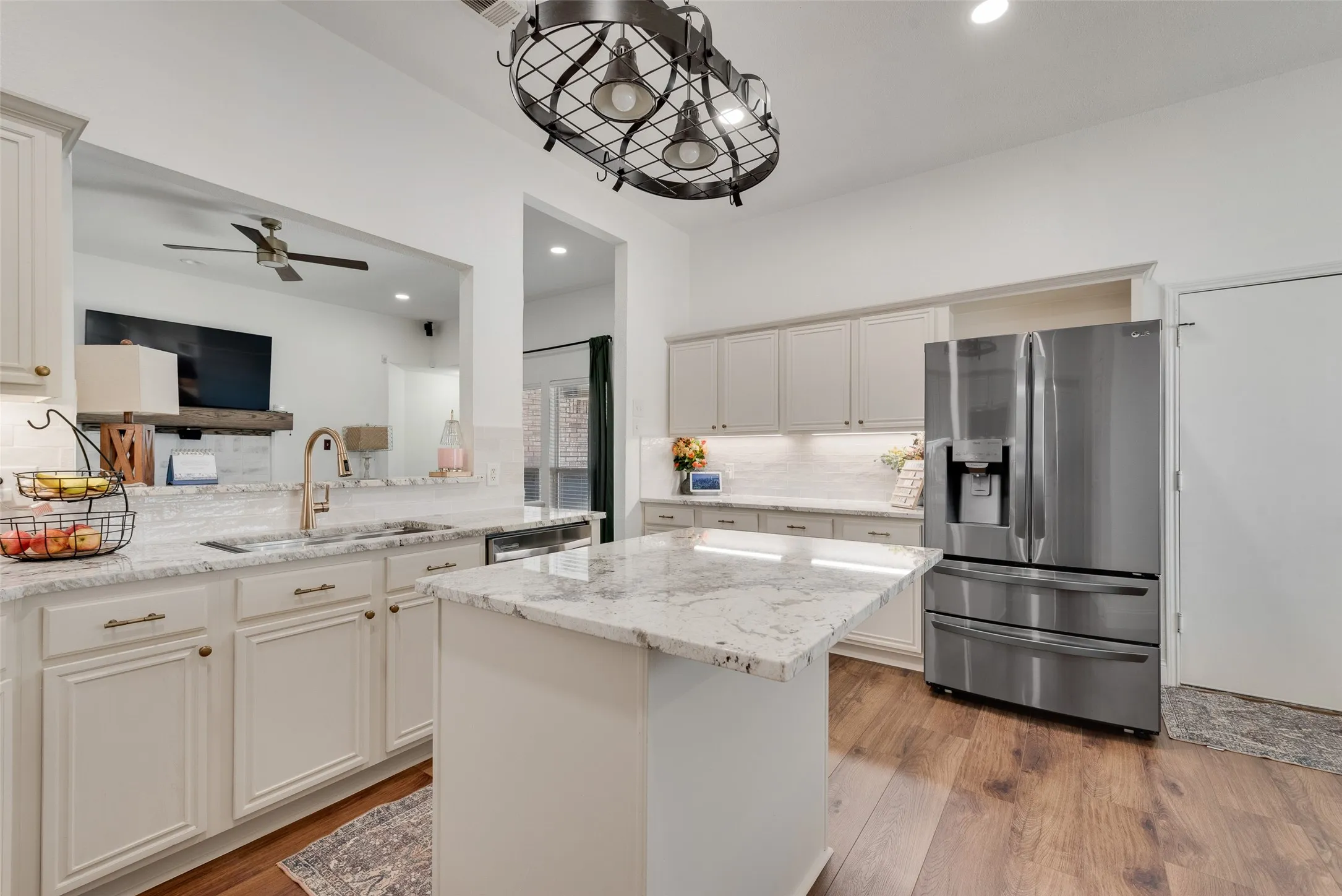 Kitchen featuring light-toned cabinetry, stainless steel appliances, a center island with a stone countertop, wood-finish flooring, and recessed lighting