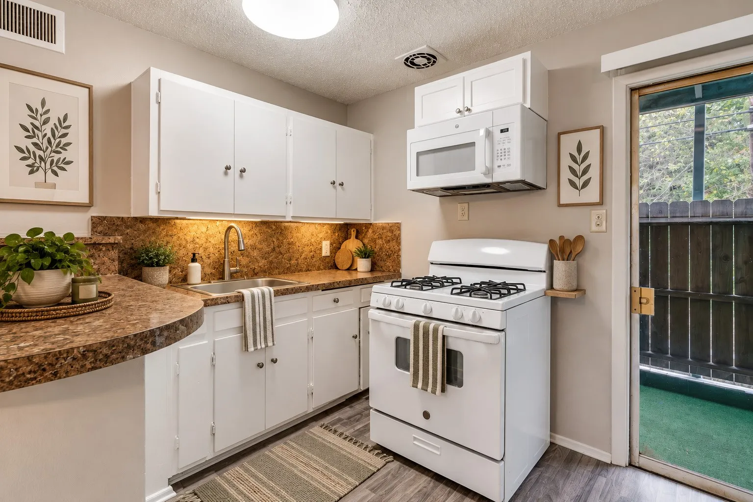 Kitchen featuring white cabinetry, stone-look countertops, a stainless steel sink with a gooseneck faucet, a white gas range, and a built-in microwave
