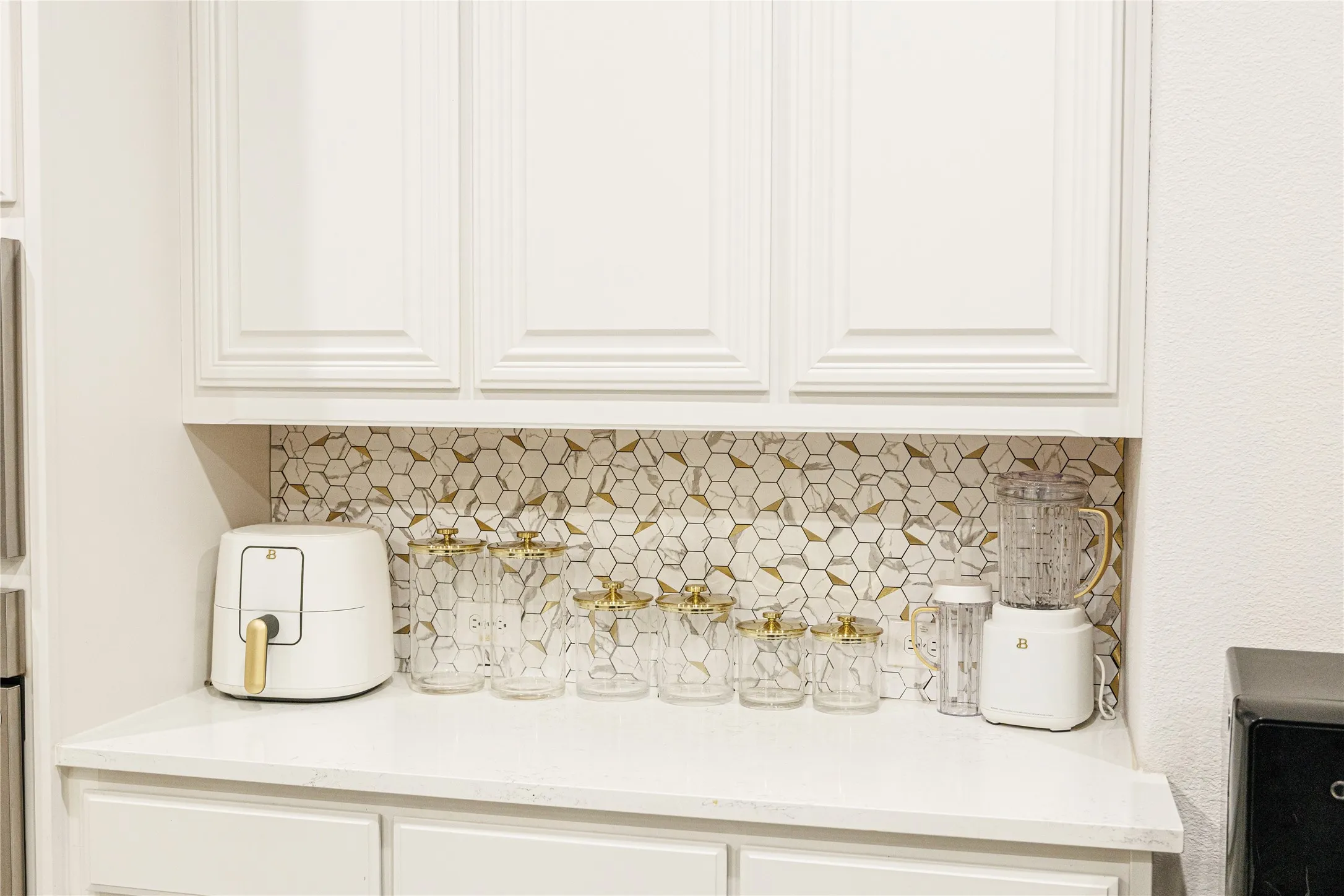 White paneled cabinetry with a white countertop and a hexagonal tile backsplash