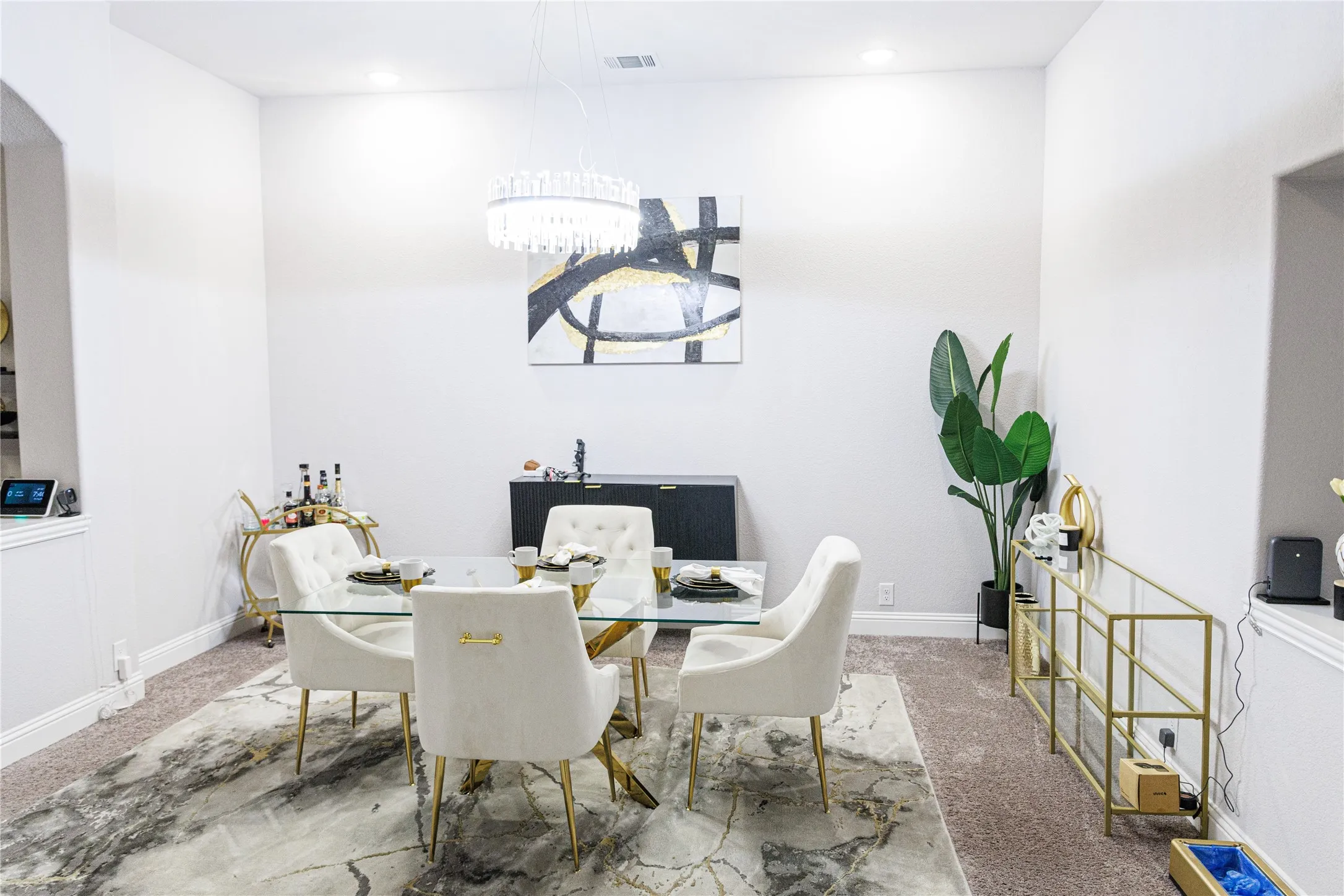 Recessed lighting illuminates this dining area with a contemporary chandelier, wall art, and a built-in archway