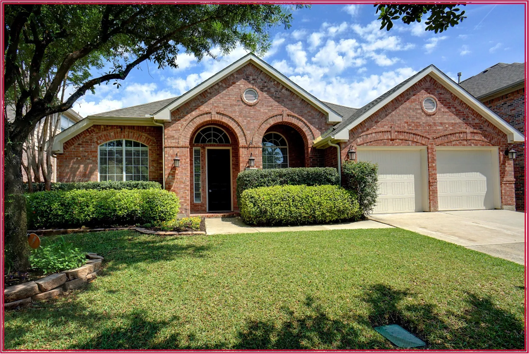 Brick exterior with arched entryways, a two-car garage, and established landscaping