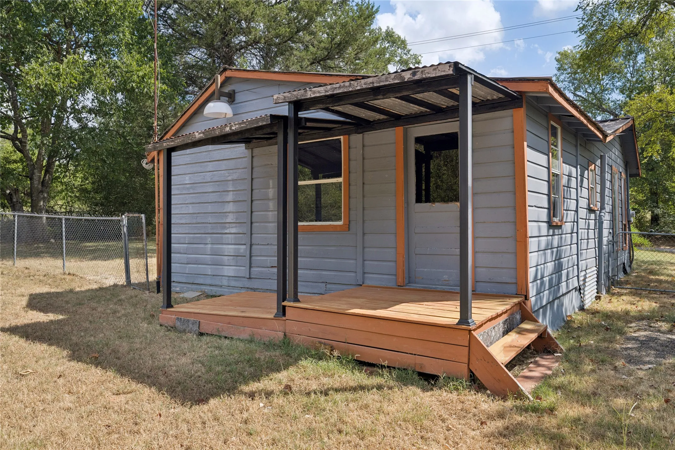 Wood-plank exterior with a covered porch featuring wood flooring and a corrugated metal roof