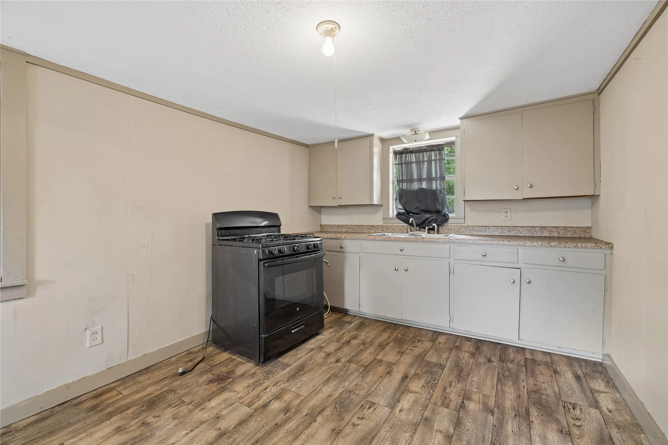 Wood-finish flooring, built-in cabinetry, laminate countertops, and a gas range