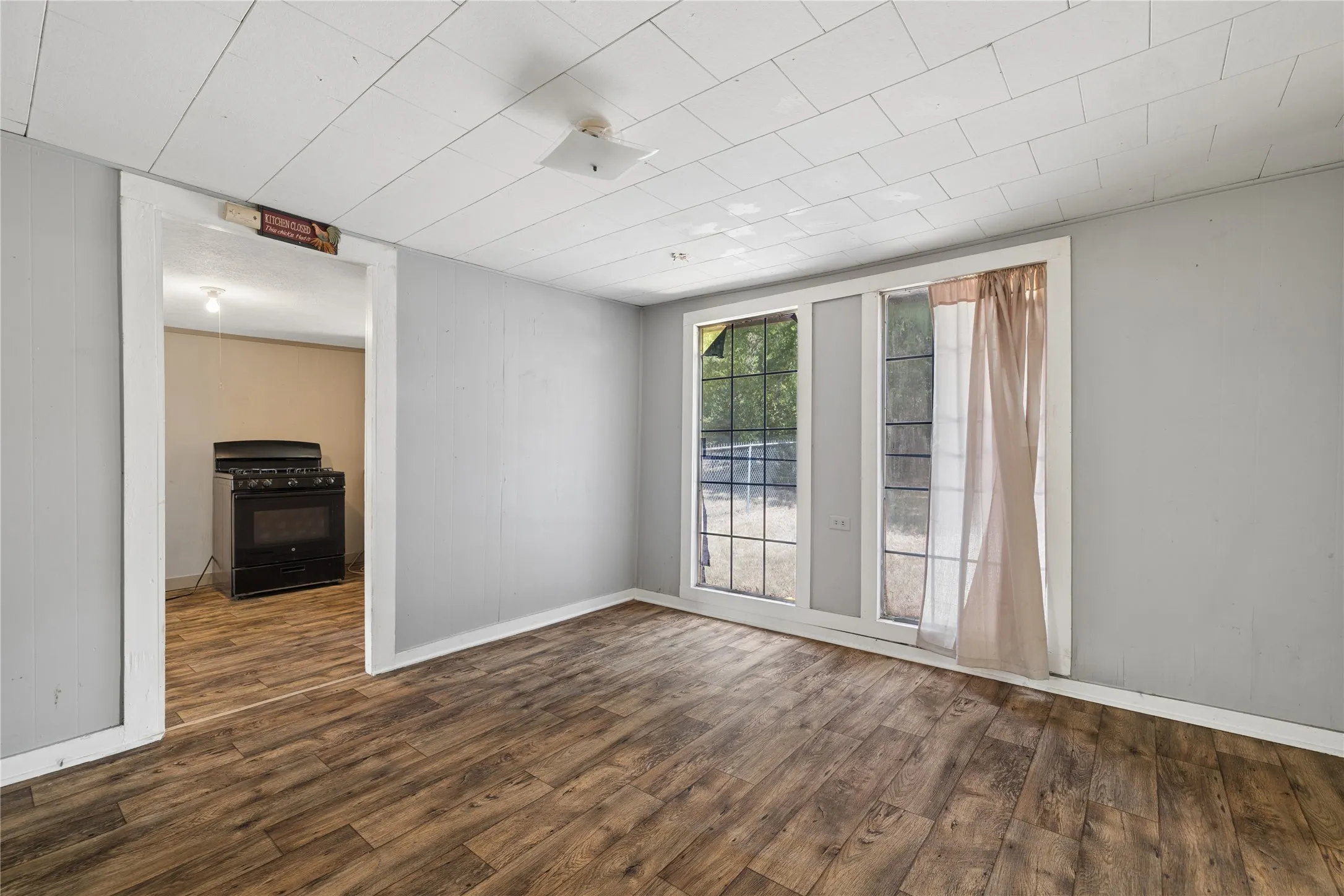 Wood-finish flooring throughout, multiple windows, and a flush mount ceiling light fixture