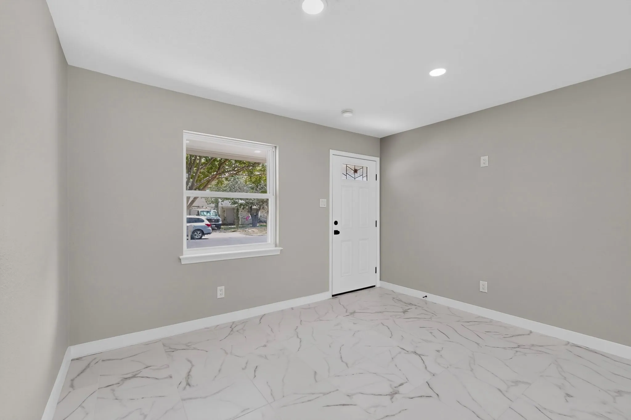 Recessed lighting, white-framed window, gray wall tones, white baseboards, and marble-look flooring