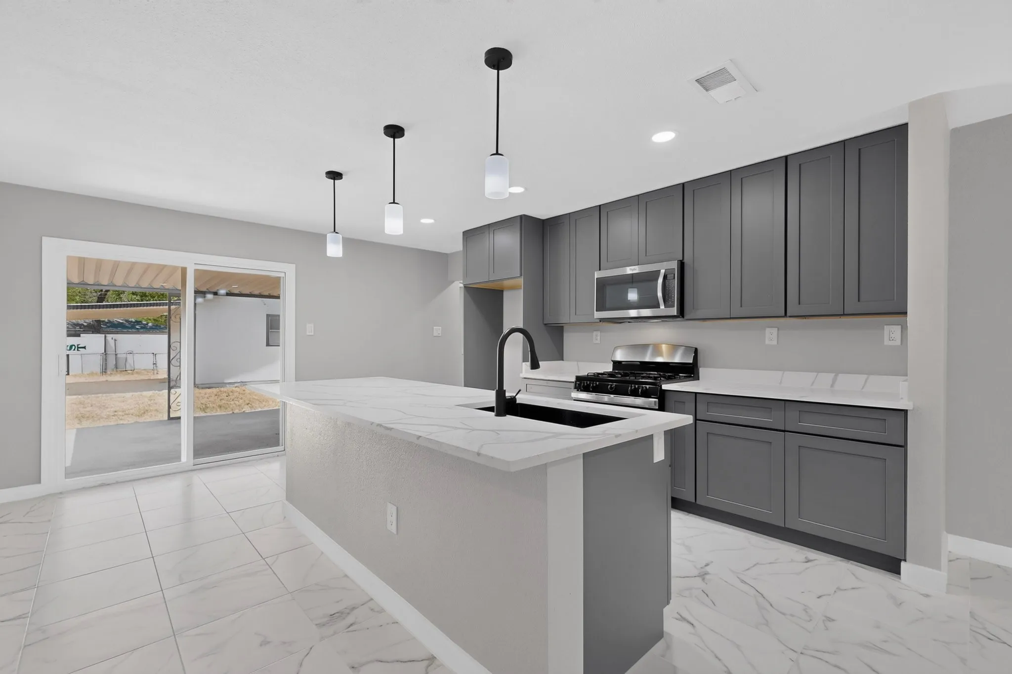 Kitchen featuring a center island, white stone countertops, dark gray cabinetry, stainless steel appliances, and tile flooring