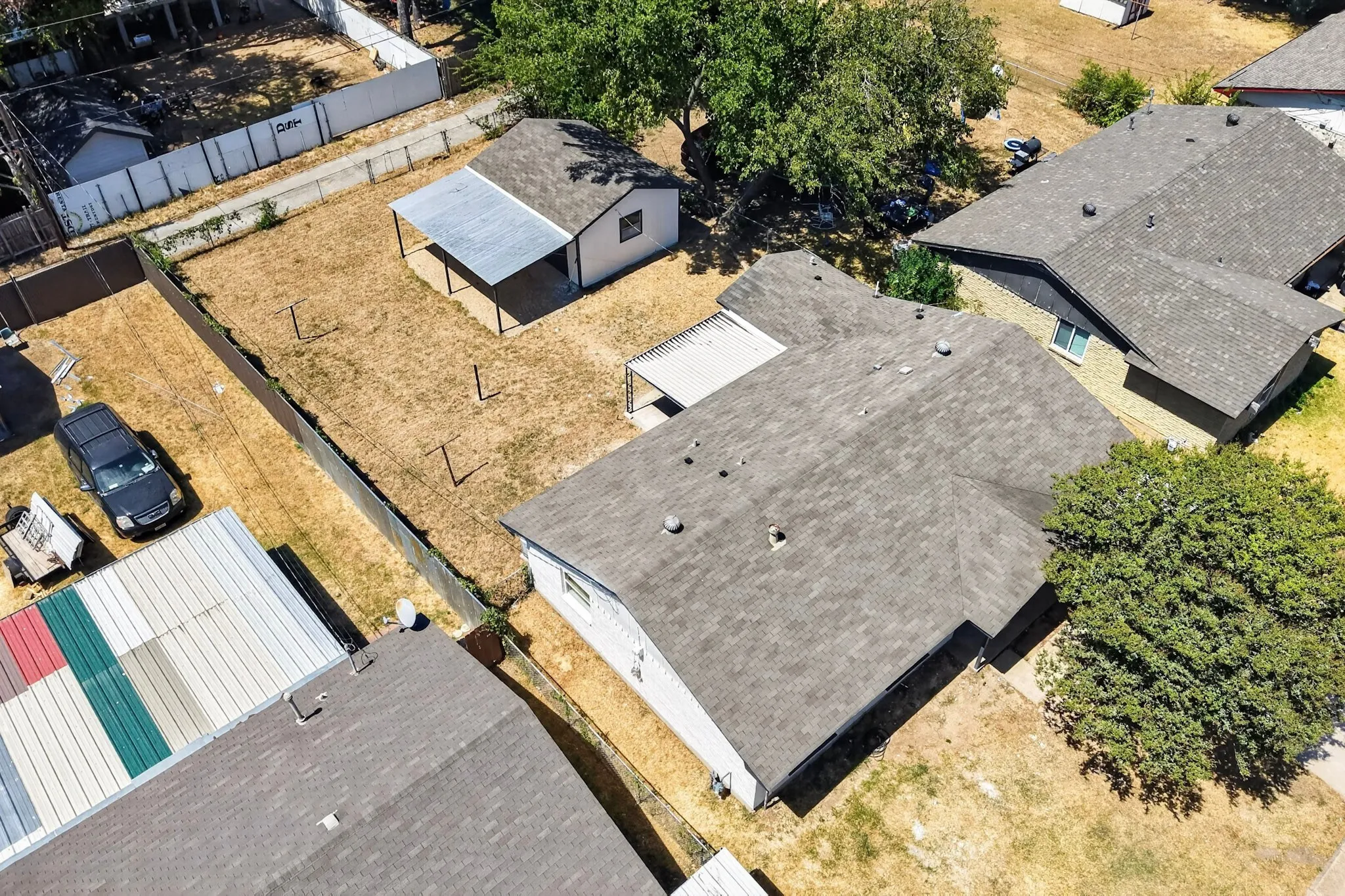 Pitched rooflines with composition shingles, an additional detached structure, and a covered patio area