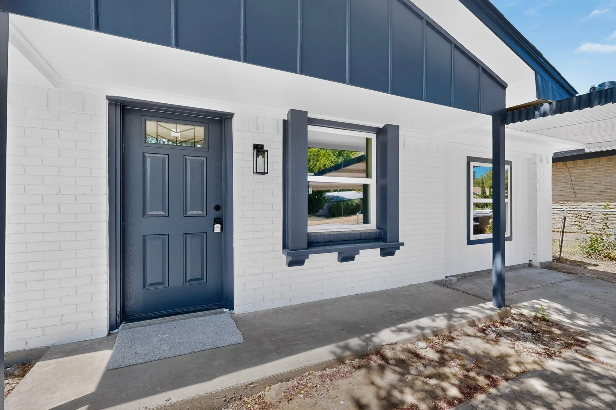 White brick exterior with a dark blue entry door