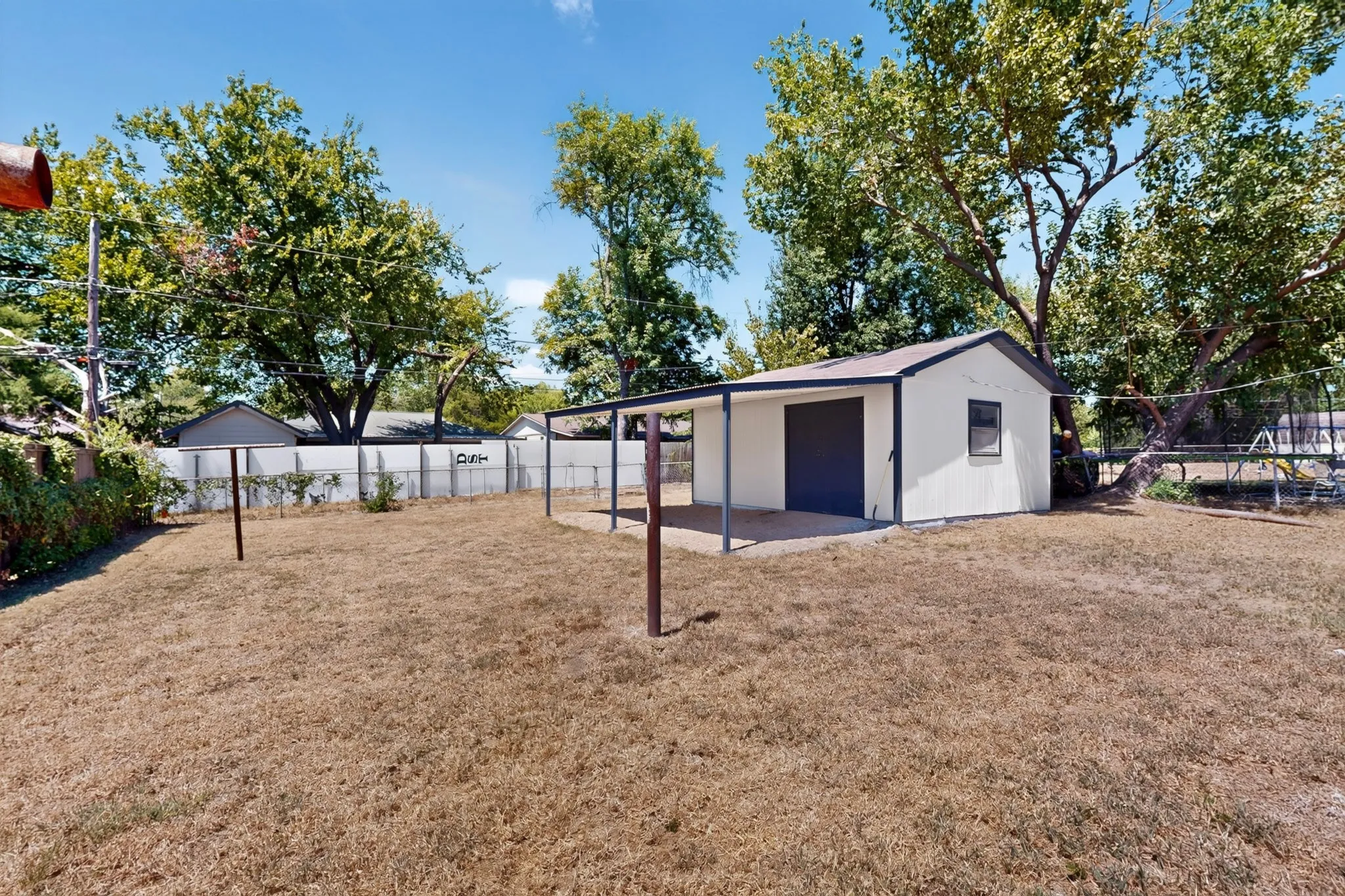 Detached auxiliary structure with an attached covered patio, featuring a panel garage door and a window