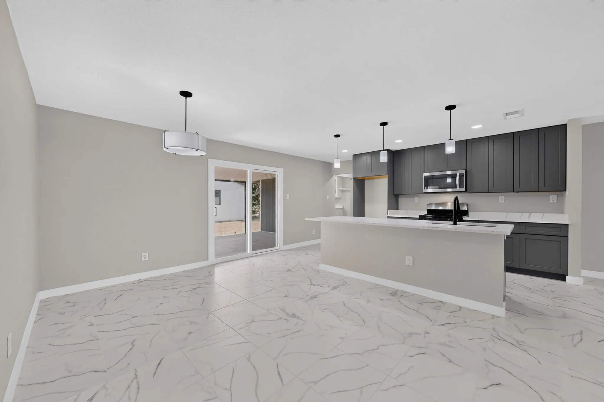 Open-concept kitchen with dark cabinetry, stainless steel appliances, a central island, and white countertops