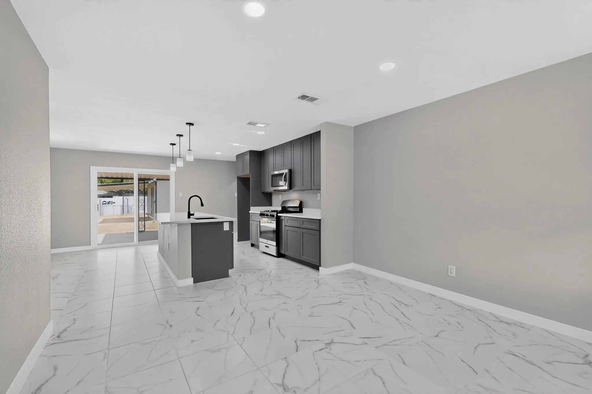 Open-concept kitchen featuring an island, recessed lighting, matte black fixtures, stainless steel appliances, and white tile flooring