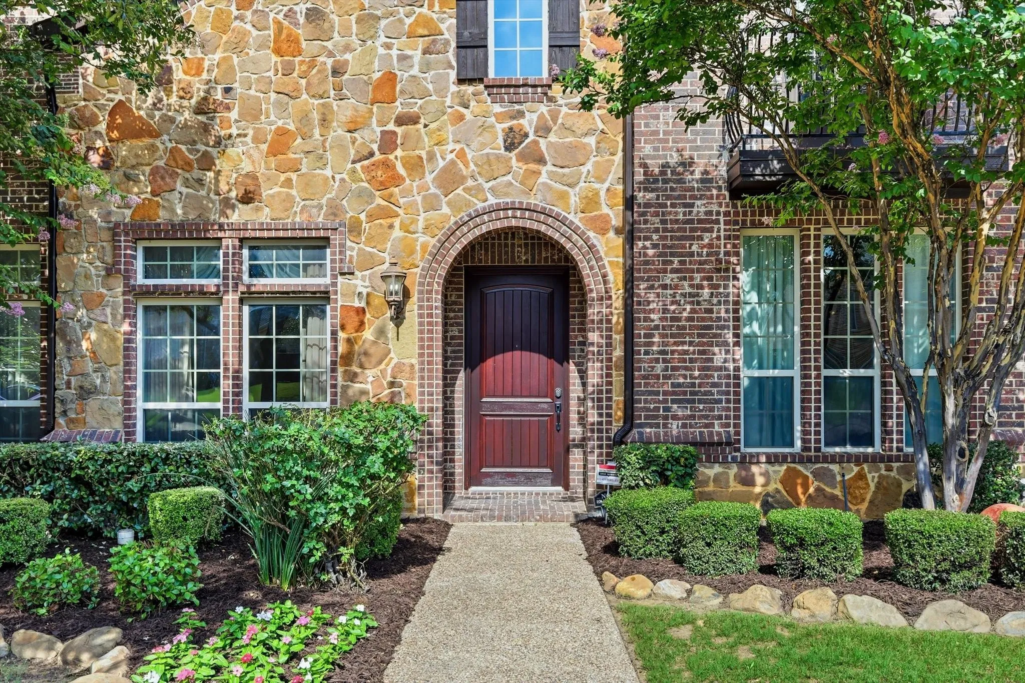 Stone and brick facade with an arched entryway, transom windows, and a dark wood door