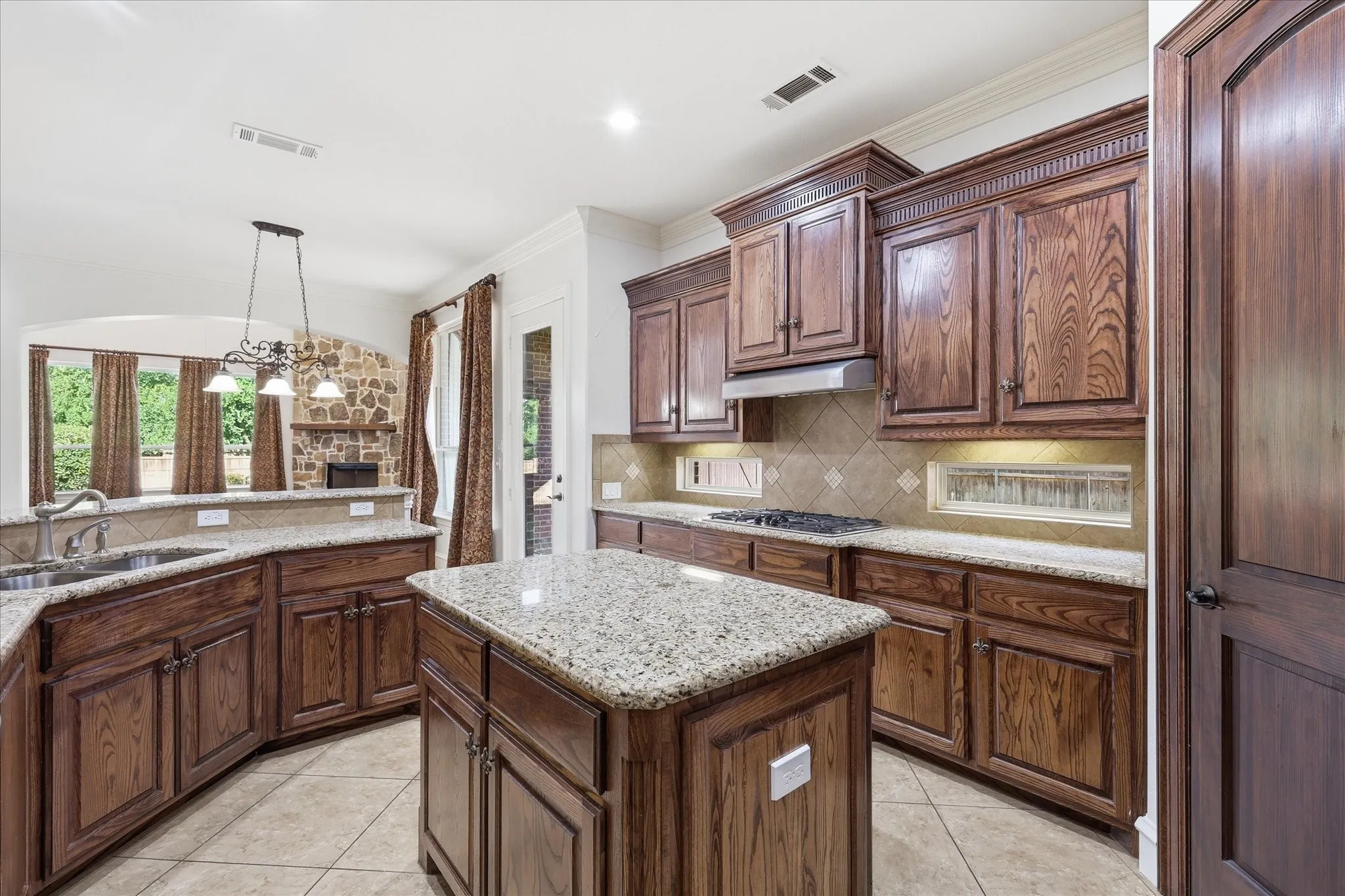 Kitchen featuring a central island, wood cabinetry, granite countertops, and tile flooring