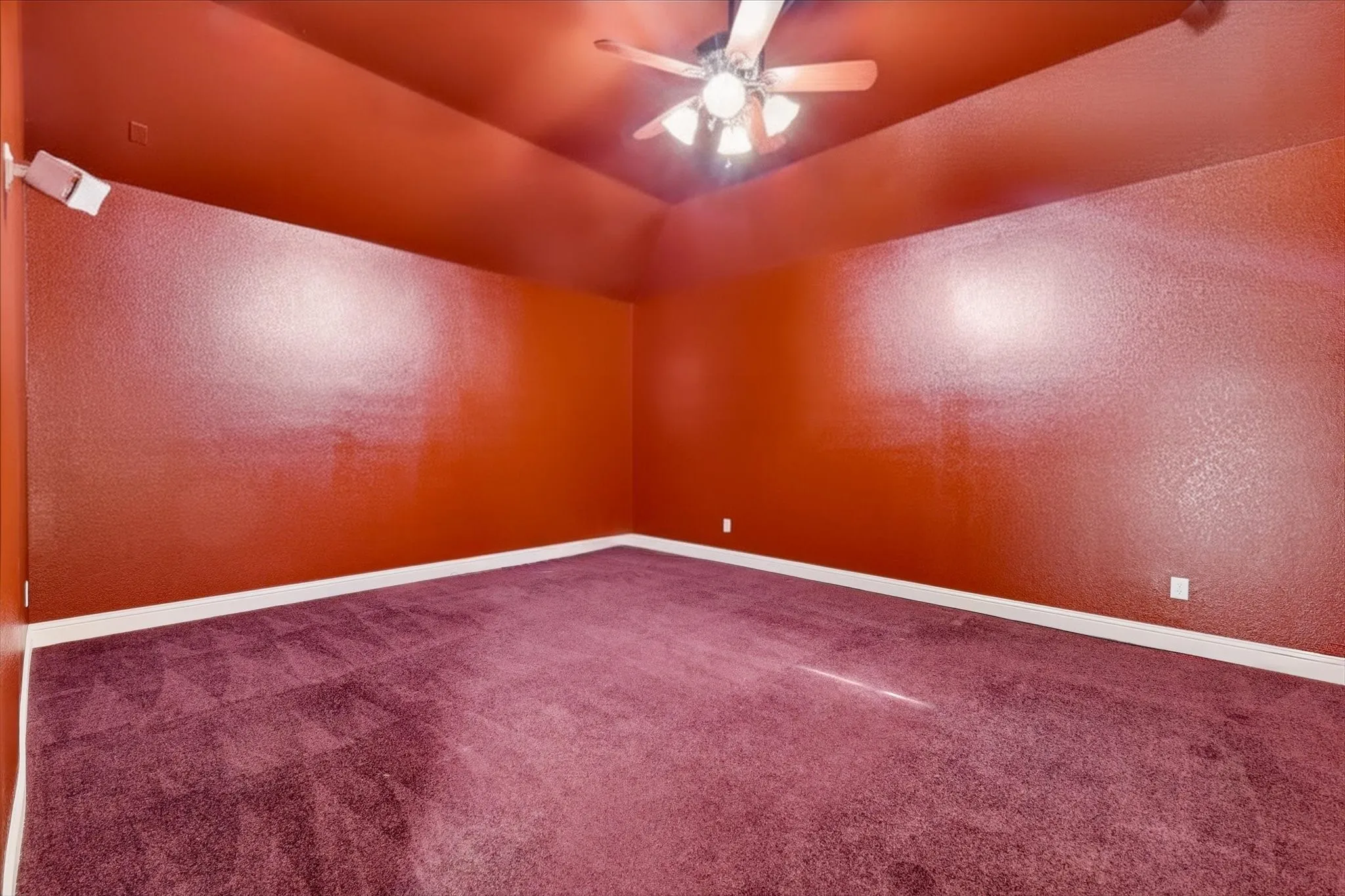 Vaulted ceiling with an integrated ceiling fan and light fixture, plush carpeting, and wall-mounted speakers