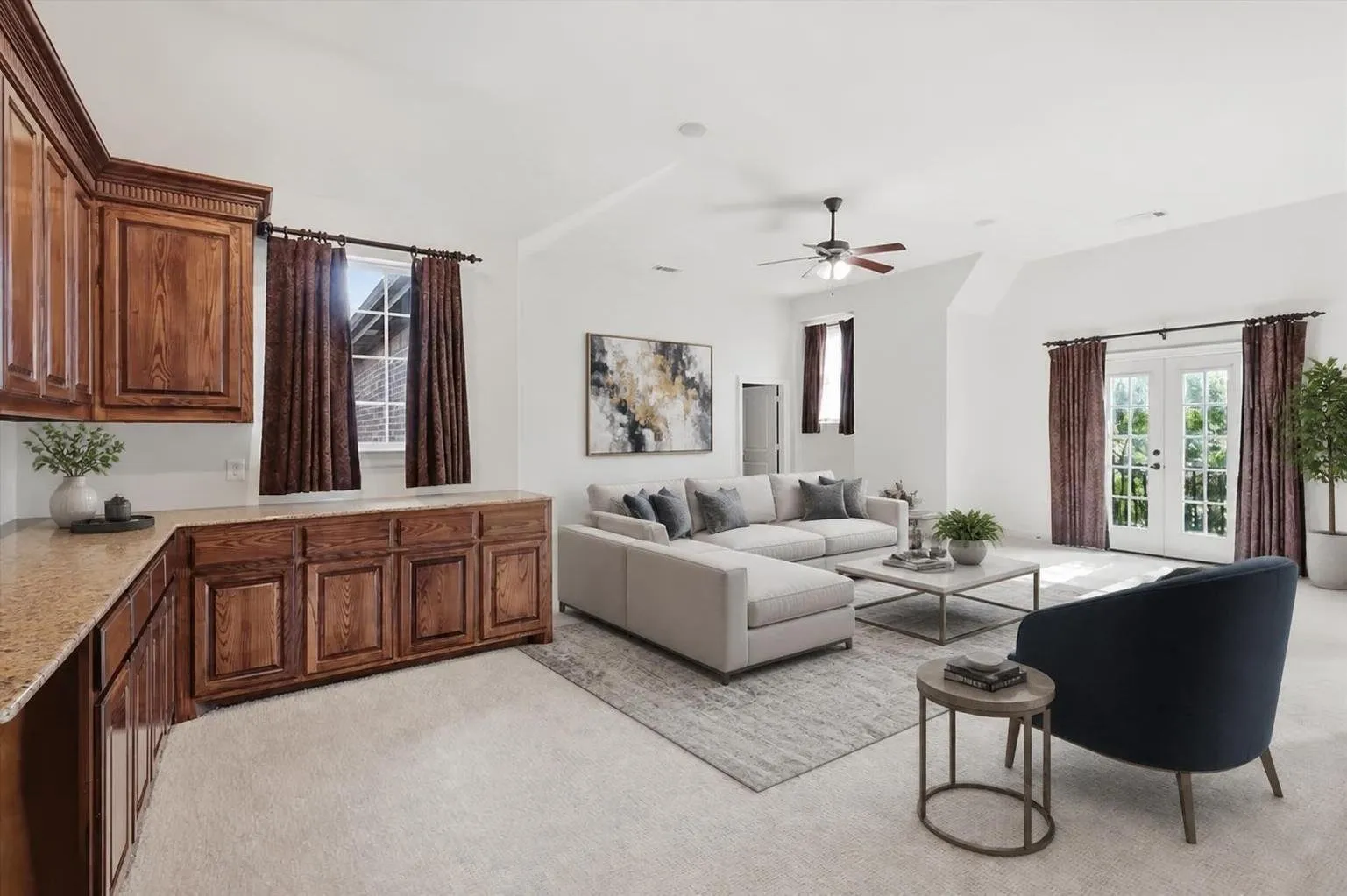 Built-in wooden cabinetry with a light-toned countertop, double French doors, a ceiling fan, vaulted ceiling, and carpeted flooring