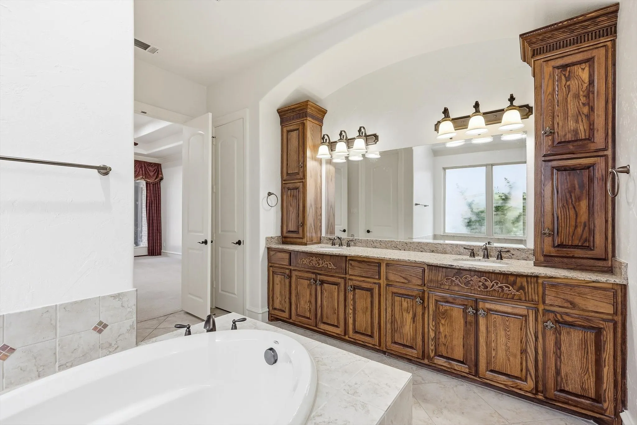 Dual vanity with wood cabinetry, light-colored countertop, and integrated sinks